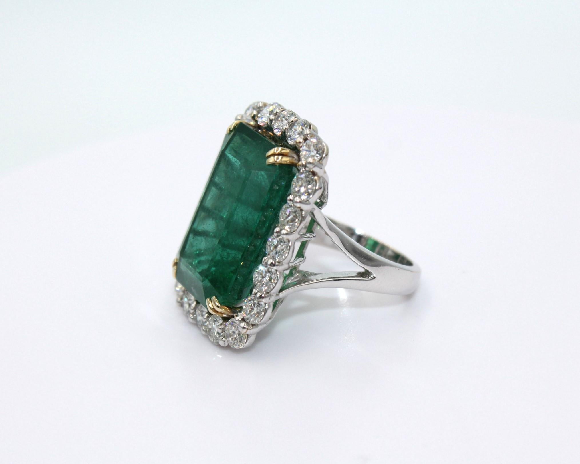 28.78 carats Emerald Cut Zambian Emerald, framed with 20 round diamonds totaling a diamond weight of 4.13 carats. 

This stunning Emerald Diamond Ring will highlight your elegance and uniqueness. 

Item Details:
- Type: Ring
- Metal: 18K Gold
-