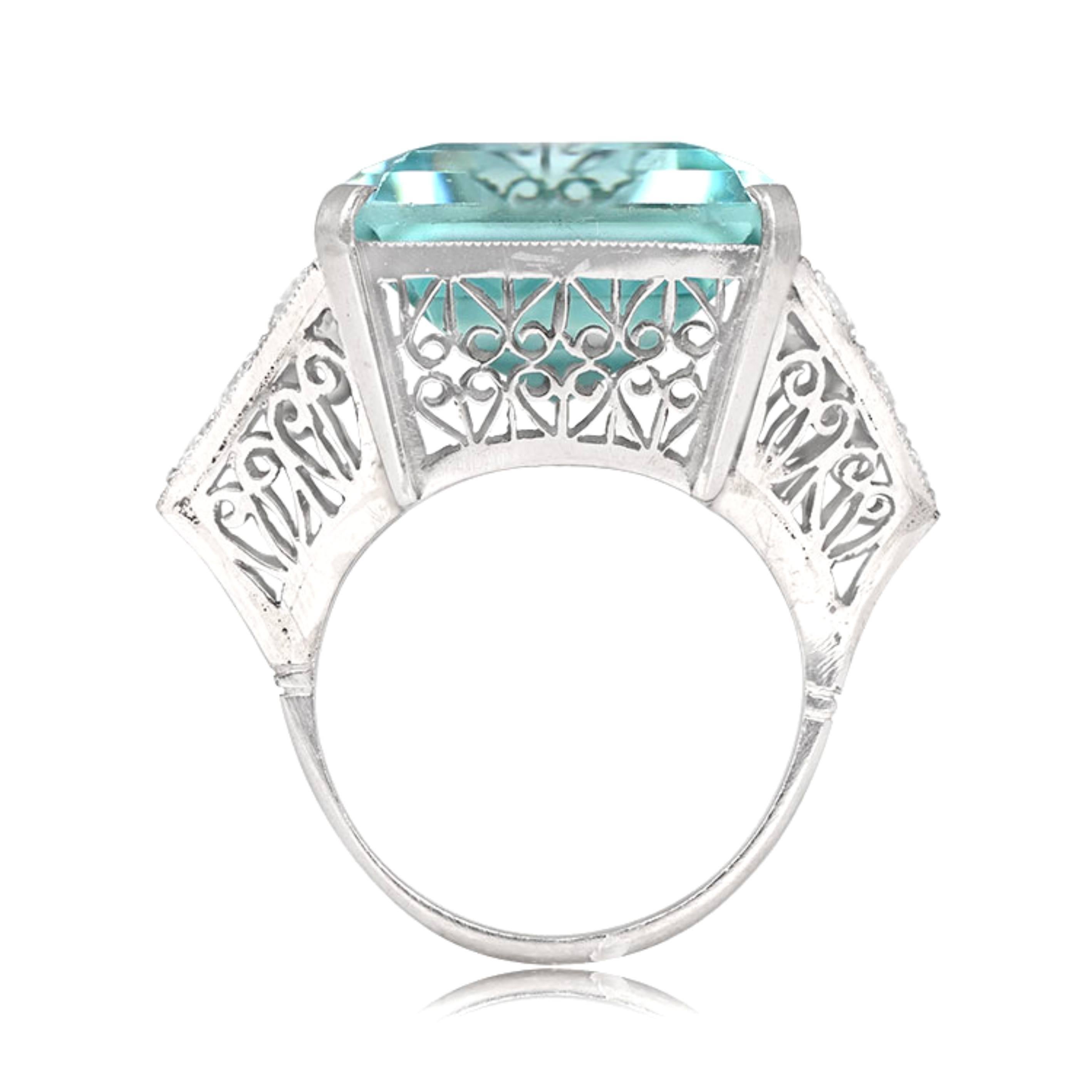 This exquisite platinum ring showcases a magnificent emerald-cut aquamarine weighing around 28 carats, securely set in prongs to ensure its stunning beauty is displayed to perfection. The ring's shoulders have a unique triangular shape and are