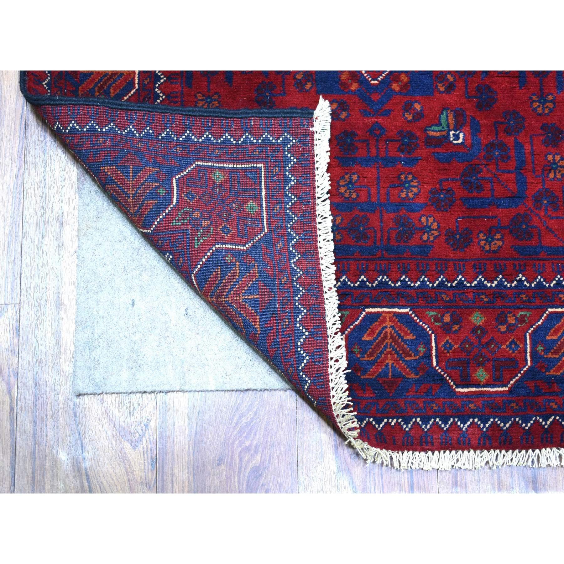 Il s'agit d'un véritable tapis d'Orient, unique en son genre, d'un rouge profond et saturé avec des touches de bleu marine, Khamyab afghan avec médaillon géométrique, en laine douce nouée à la main, en forme de couloir. Il a été noué pendant des