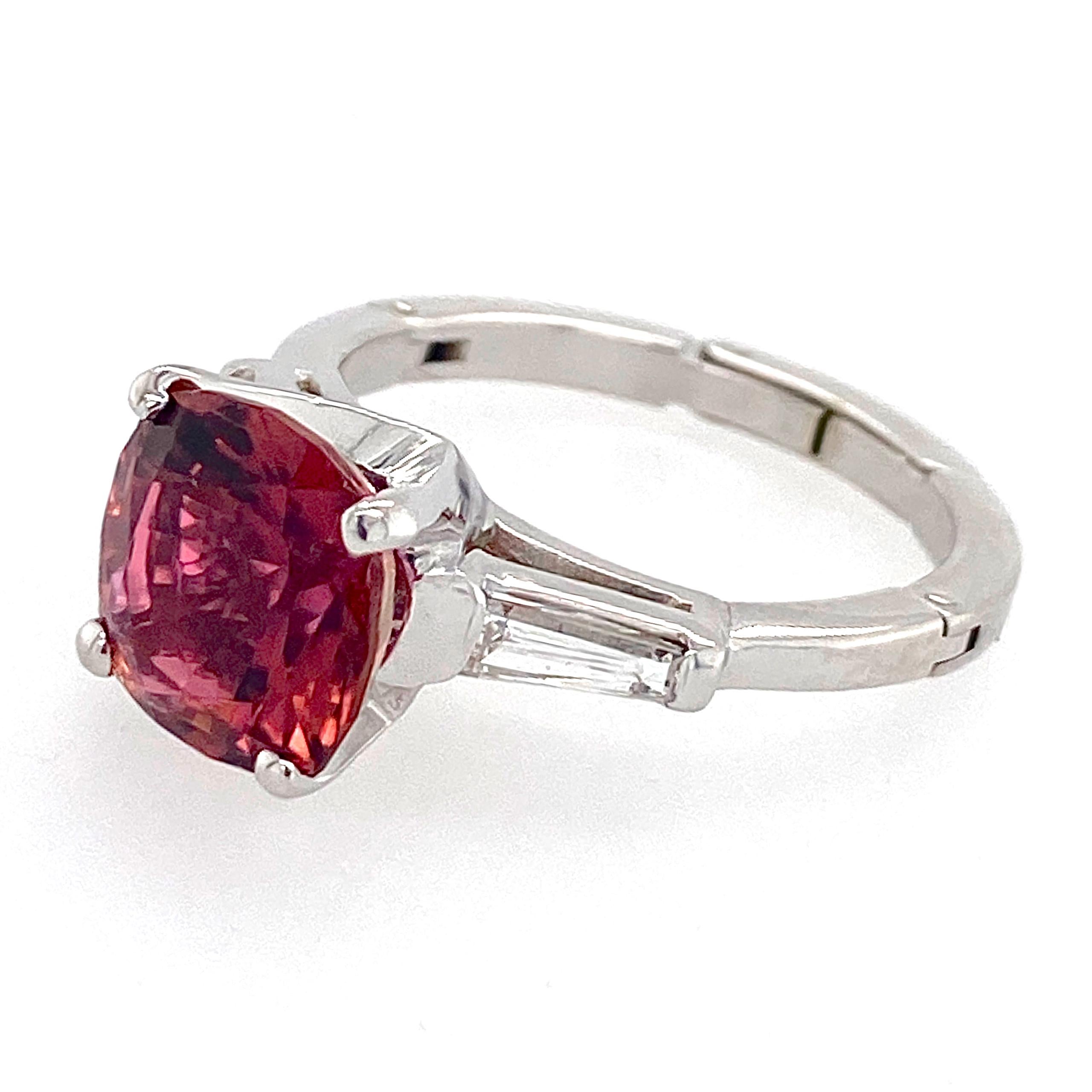 A beautiful, richly hued dark pink tourmaline, ethically sourced and lovingly cut by master Tennessee gemcutter Dan Lynch, looks completely at home in a timeless three-stone setting.

The ring is a classic platinum Deco-era cathedral setting with