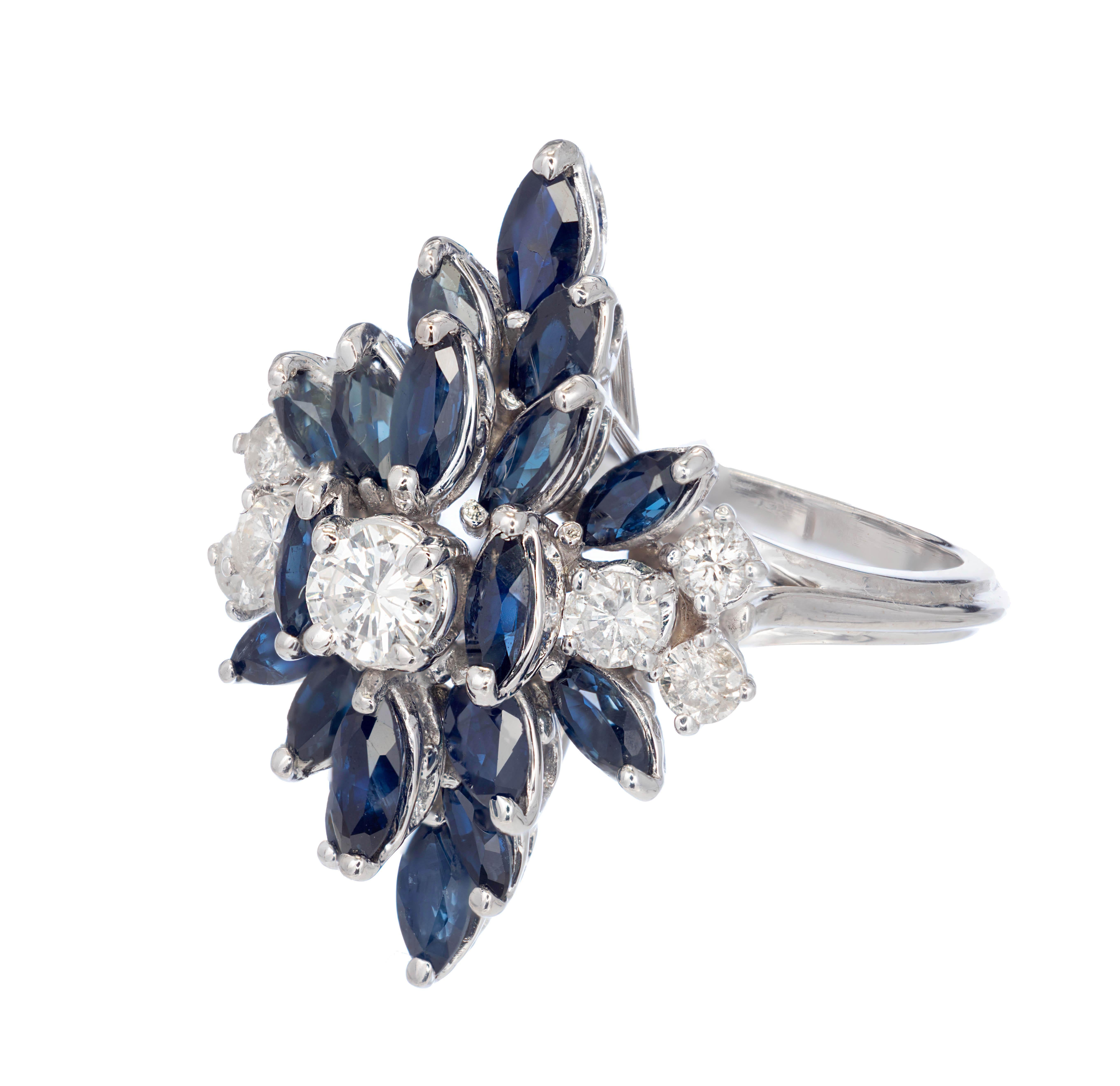 1960's Sapphire and diamond starburst cluster cocktail ring. Round brilliant cut center diamond with sprays of marquise shaped sapphires above and below with additional round brilliant cut accent diamonds to each side in a 14k white gold setting. A