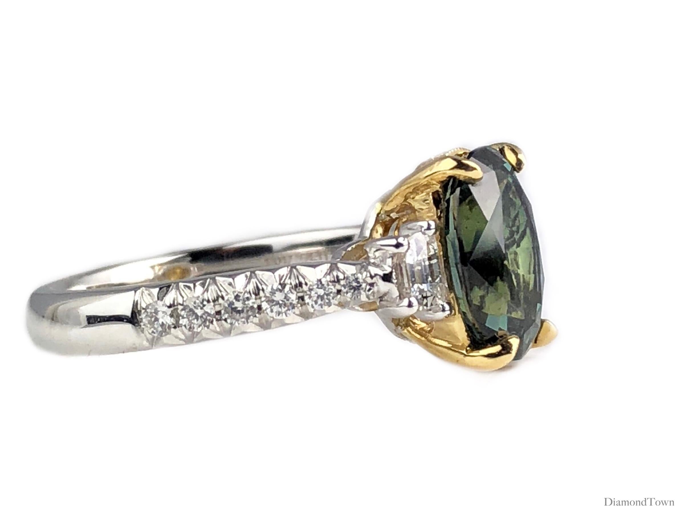 This ring features an exotic 2.90 carat oval cut Forest Green Sapphire center, flanked by half moon diamonds and additional diamonds extending down the side shank (total diamond weight 0.57 carats). An accent of yellow gold and some milgrain work in