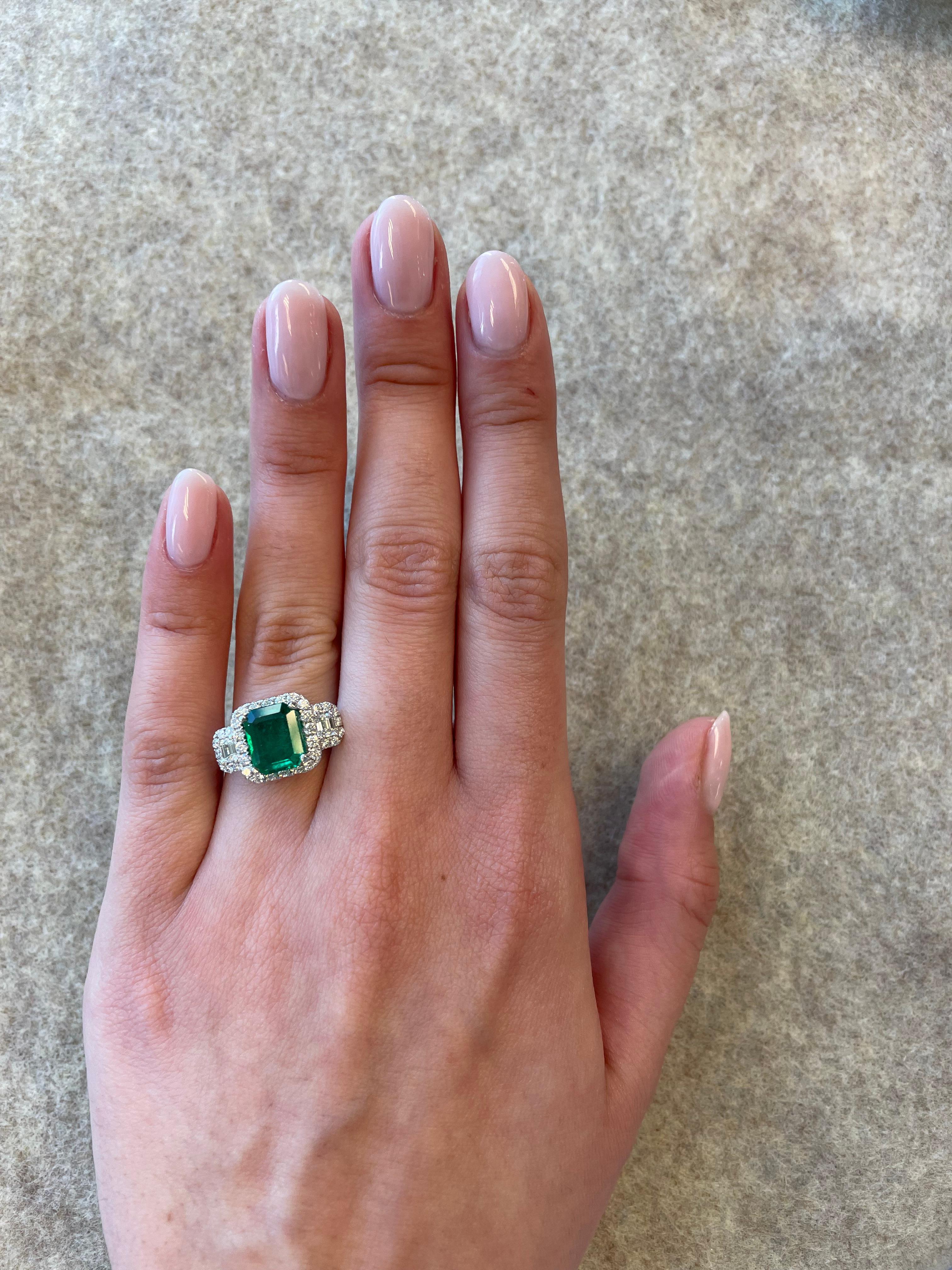 Stunning emerald and diamond three stone ring with halo. By Alexander of Beverly Hills. 
2.91 carats total gemstone weight.
1.82 carat emerald cut emerald. 2 emerald cut diamonds, 0.31ct. Approximately H/I color and VS clarity. Complimented by 0.70