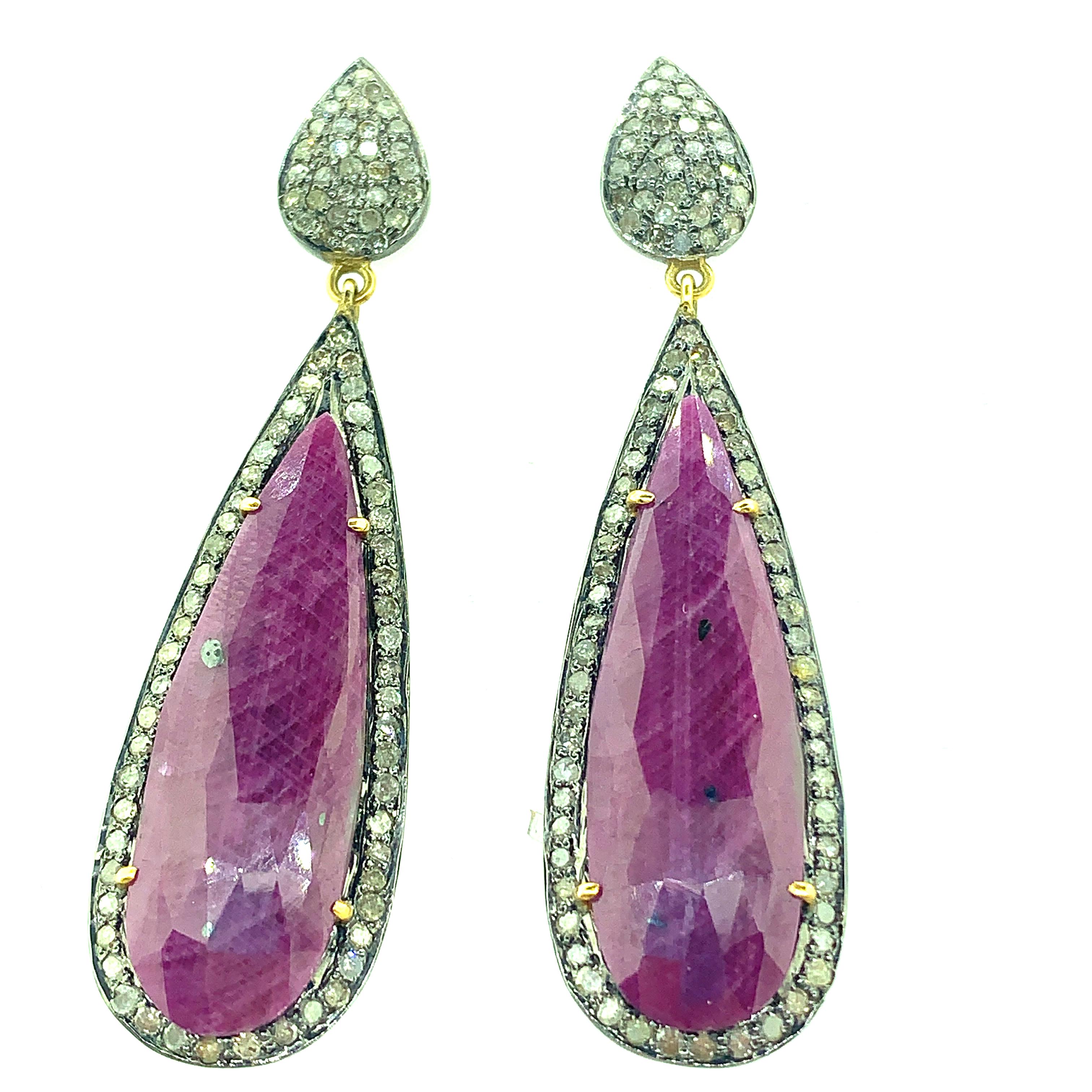 The illumination of 1.45 ct. t.w. champagne diamonds highlight the 29.20ct  pear -shaped real ruby. Set in oxidize sterling silver this hanging earring measures 2 1/2 inch long. Buffed to a brilliant oxidize luster, this post earring secure