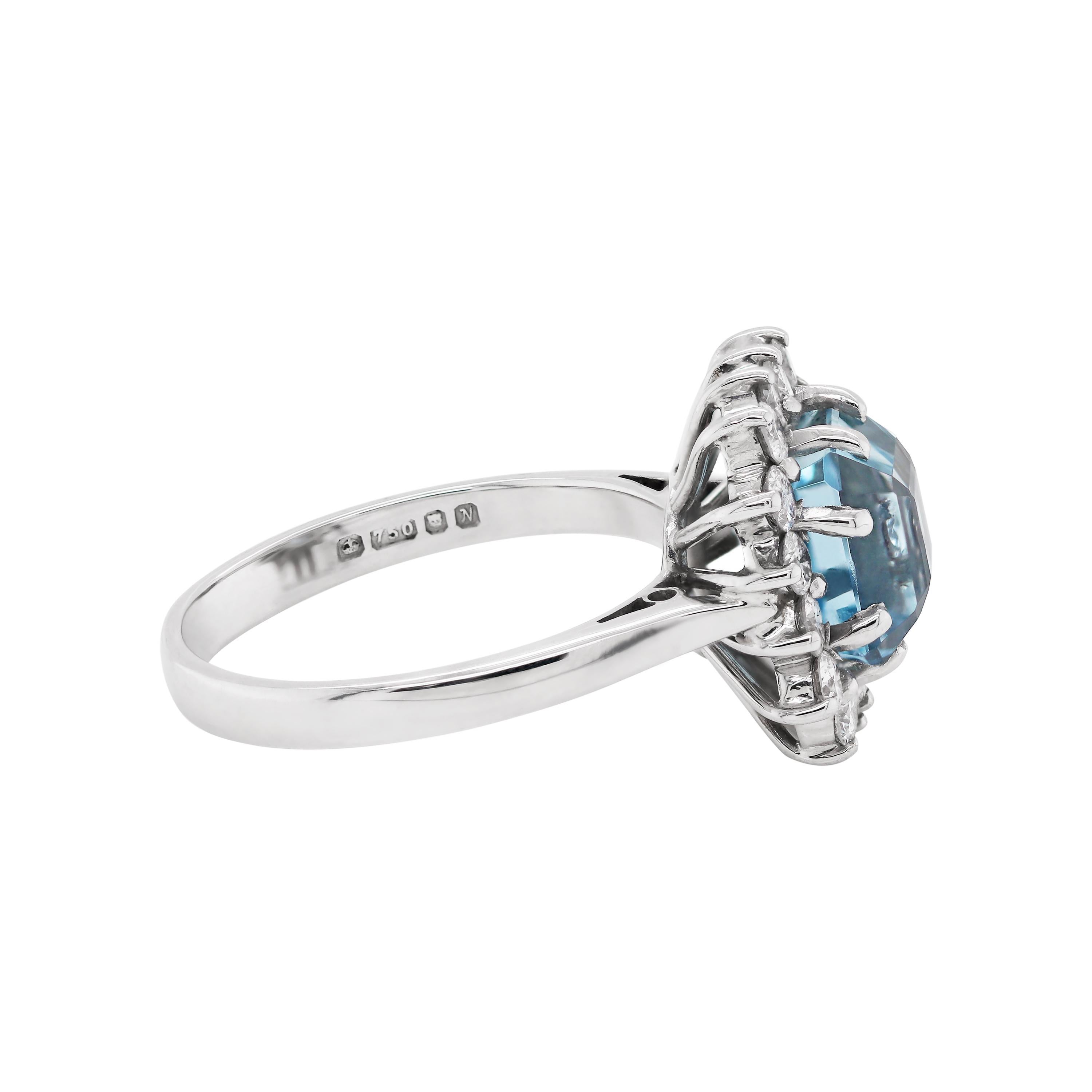 This gorgeous engagement ring features a 2,92ct square emerald cut Aquamarine mounted in a four claw, open back setting. The translucent blue stone is beautifully surrounded by 16 fine quality round brilliant cut diamonds weighing a total