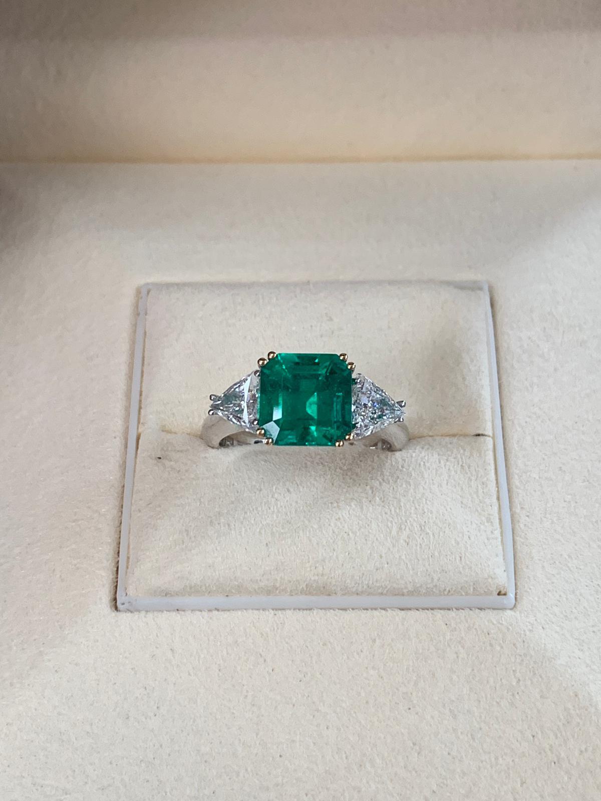 Beautiful 2.93 carats of Colombian Emerald, surrounded by 2 white trillion cut diamond 0.92 total carats. Set on 4 prong 18k white gold.