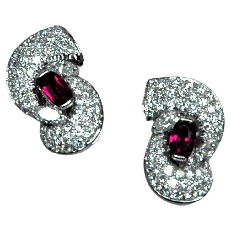 Beautiful earrings in white gold whit diamonds and rubies. Their shape is reminiscent of an embrace, made with a beautiful diamond pavé. In the center an oval ruby ​​and two navette cut diamonds.