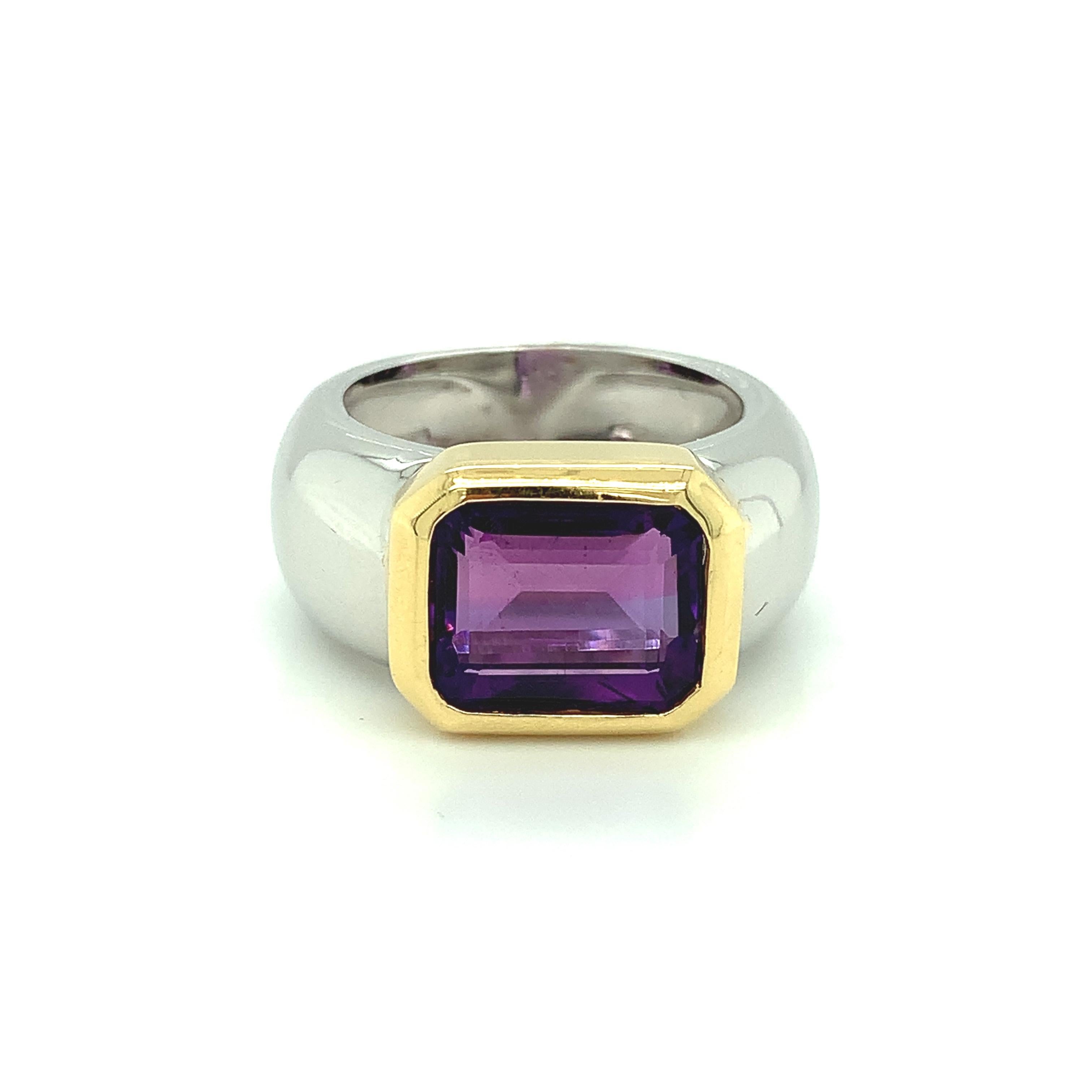 This handsome, wide-band ring features an emerald-cut amethyst of beautiful deep purple color set in a contemporary 18 karat, 2-toned gold ring! The 18k yellow gold bezel and white gold rounded band create a stunning combination of colors and shapes