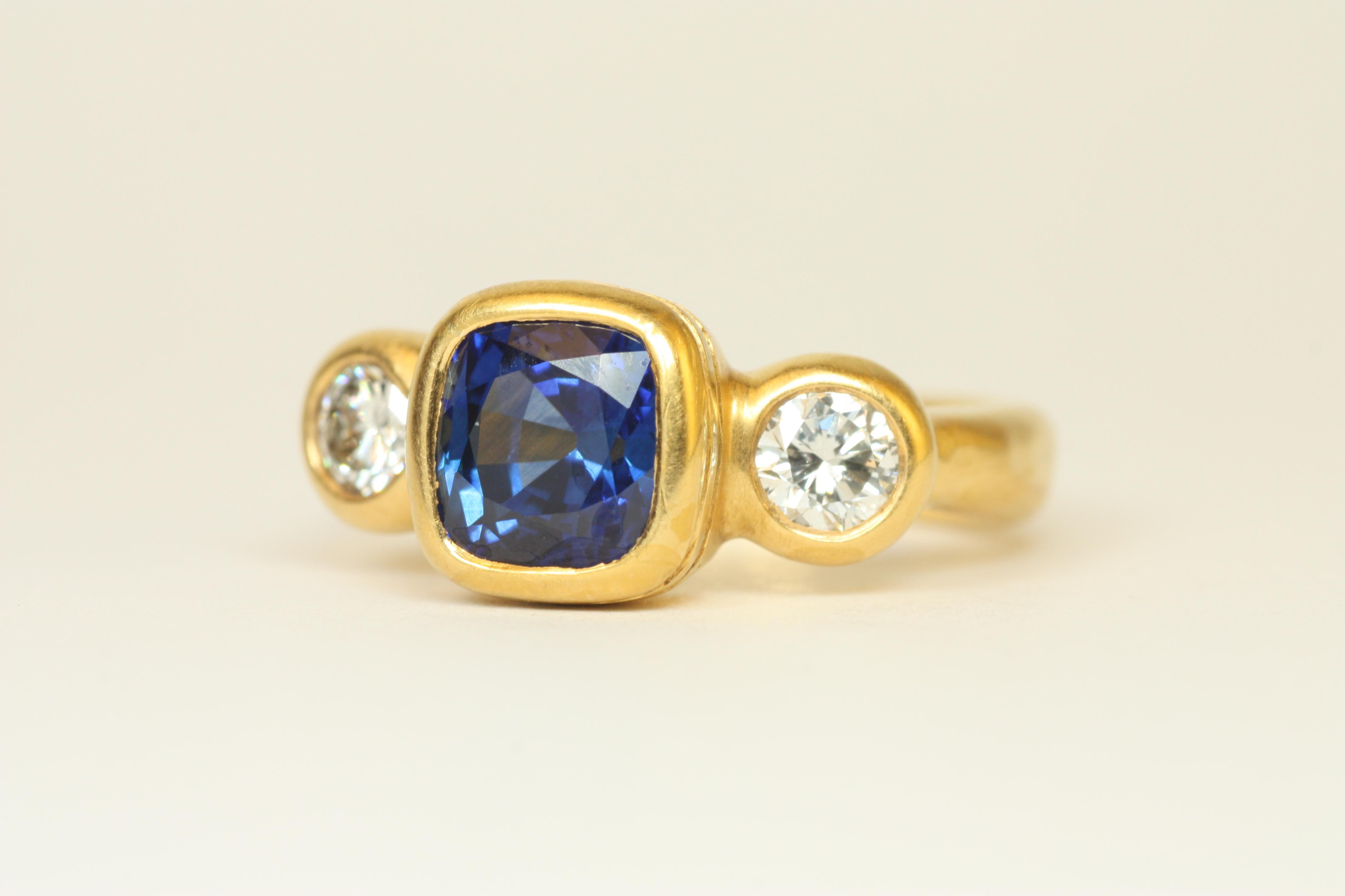 Cette variante unique de saphir bleu à taille coussin et de diamant rond de notre bague à trois pierres est une magnifique bague d'affirmation. La pierre centrale carrée en saphir offre de la profondeur et des éclats de bleu clair, et est complétée