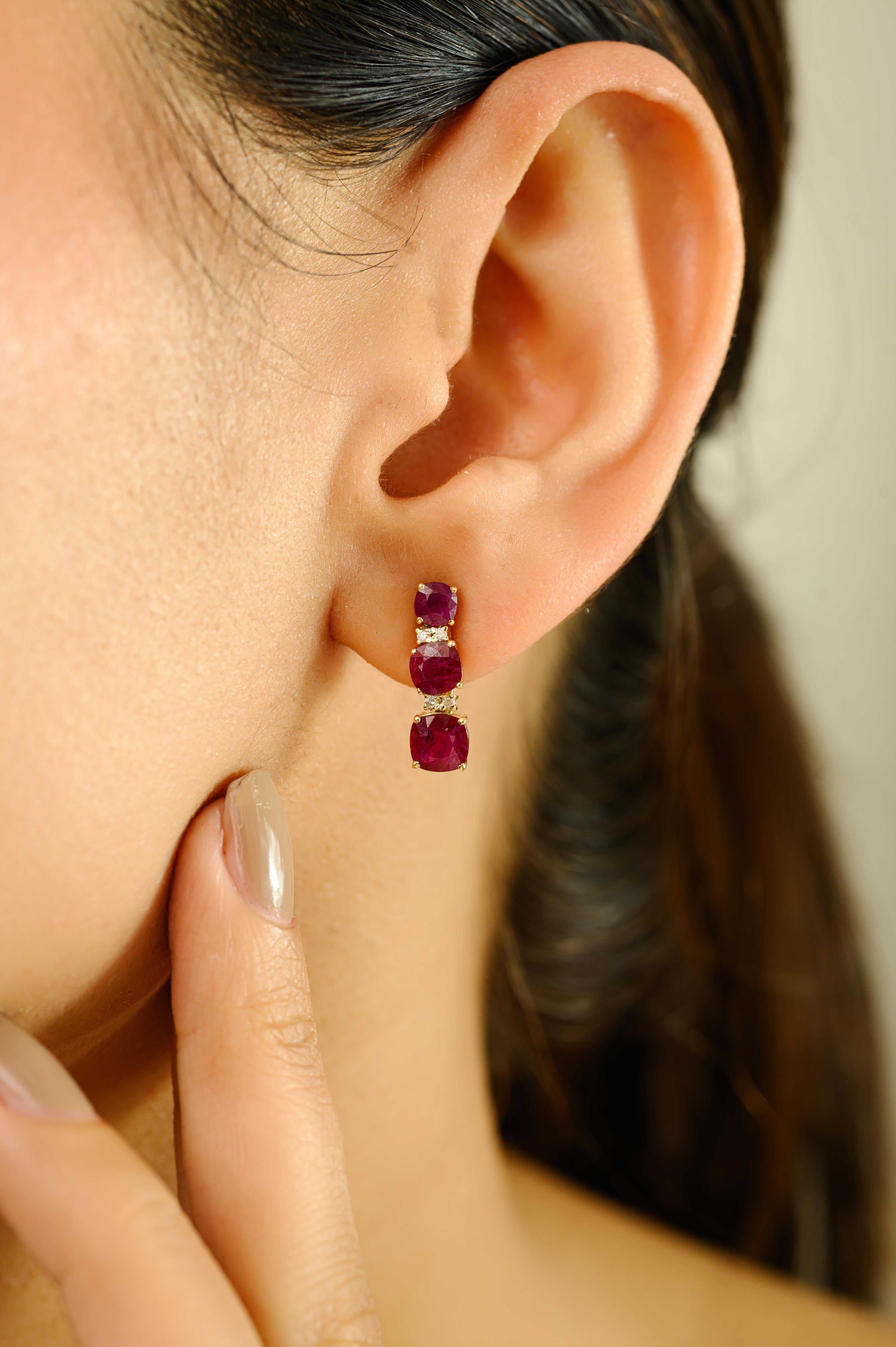 Eleva tu elegancia con estos cautivadores pendientes colgantes, bellamente elaborados en oro amarillo de 14k. Con un total de 2,95 quilates de vívido rubí dispuestos en un elegante diseño vertical de tres piedras, cada gema está facetada por