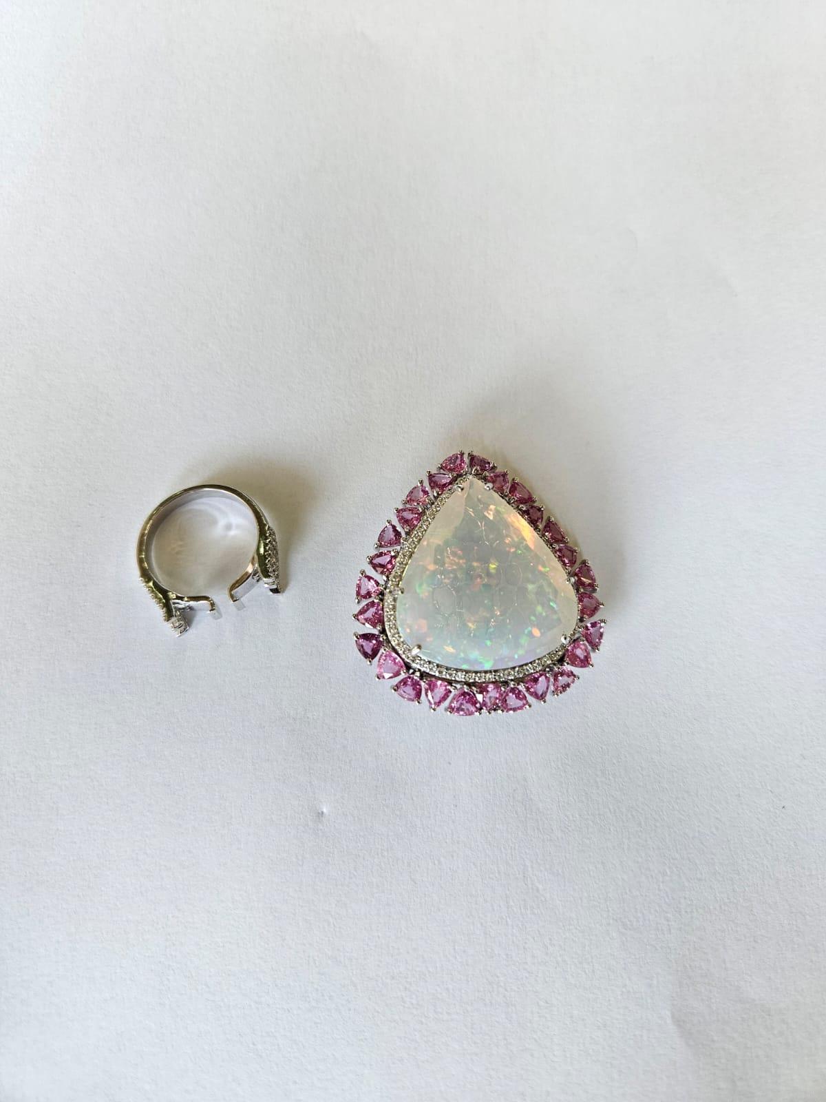 A very gorgeous and modern style, convertible Opal & Pink Sapphire Cocktail Ring / Pendant Necklace set in 18K White Gold & Diamonds. The weight of the Opal is 29.59 carats. The Opal is of Ethiopian origin. The weight of the Pink Sapphires is 6.98