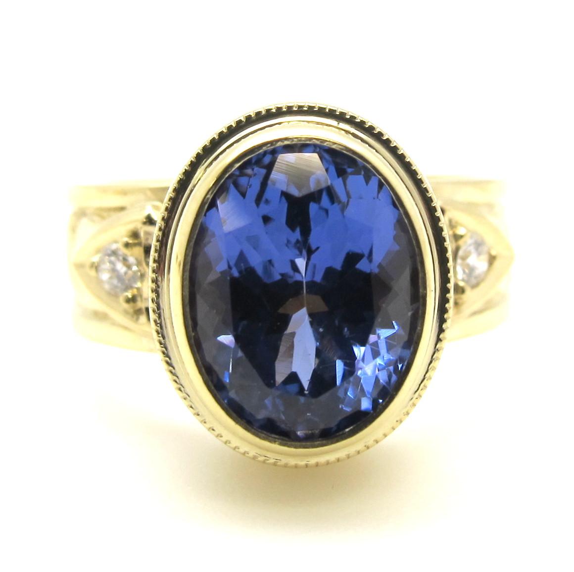 This ring features a beautiful, violetish-blue tanzanite, measuring 10.00 x 7.50mm and weighing 2.98 carats. It is bezel set in a handmade, 18k yellow gold setting, made by our Master Jewelers in Los Angeles. The attention to detail and level of