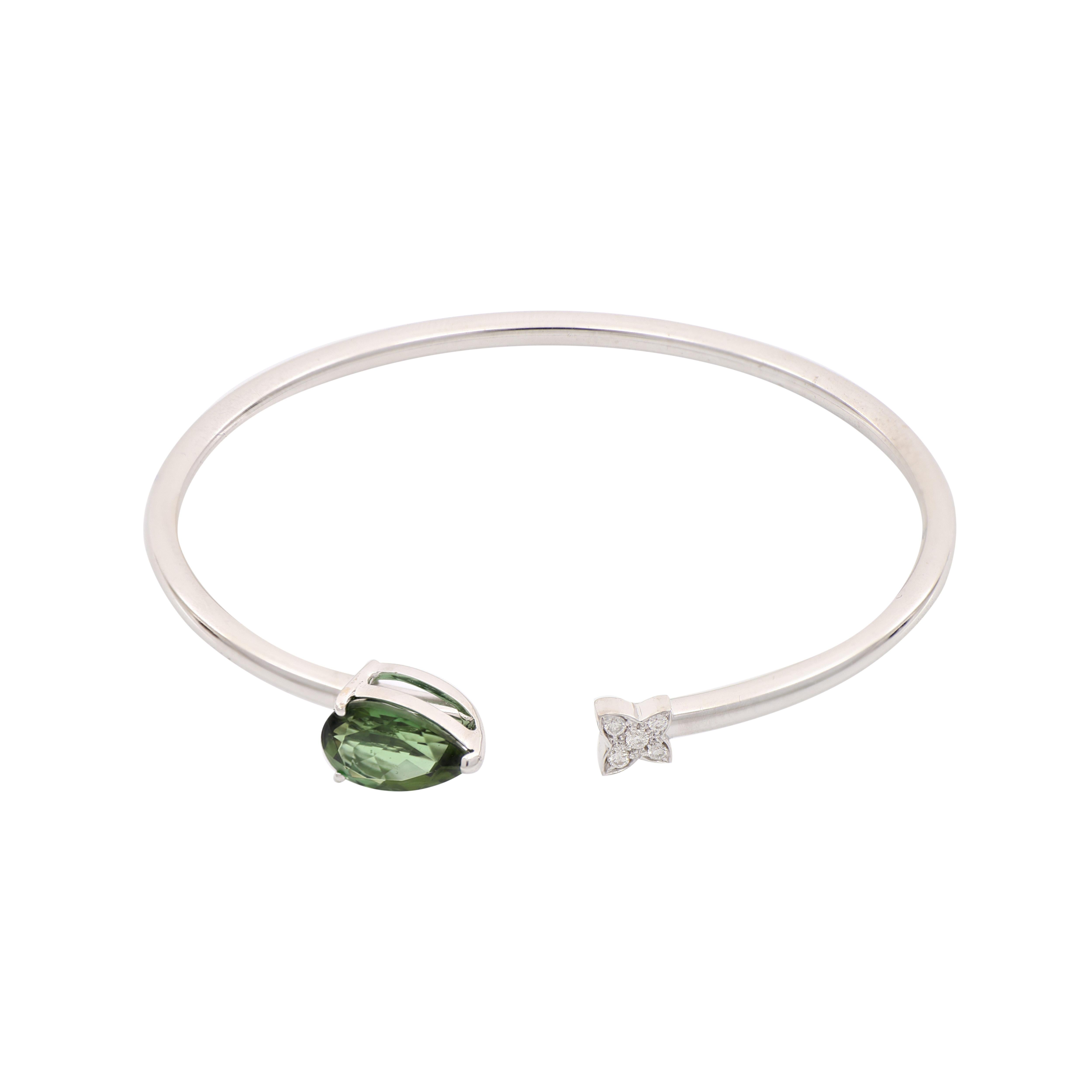This sleek, 18 Kt white gold open-cuff bangle bracelet features a pear-cut green tourmaline on one end and white diamonds on the other end. Tourmaline is the newer October birthstone that can help polarize people's emotions and energy. It is said to