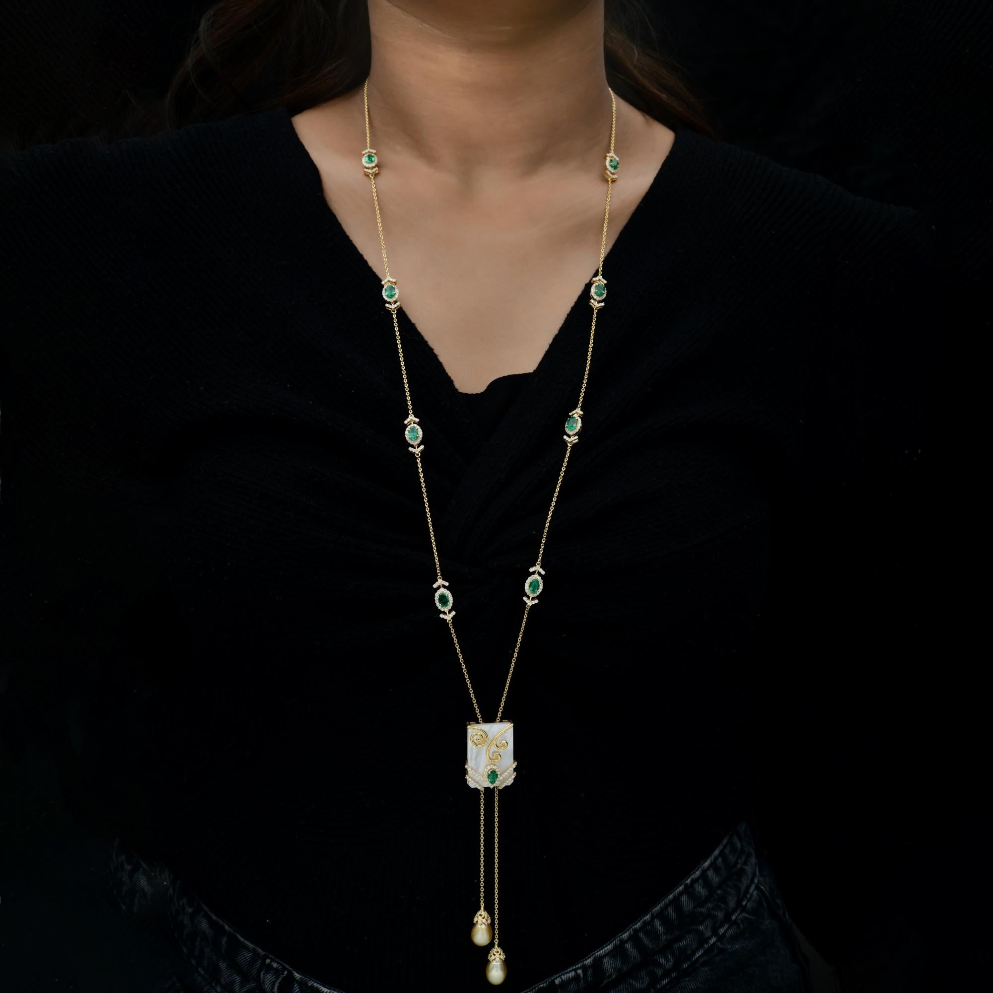 29Tcw Art Deco Smaragd Perlmutt Lariat Diamant 18 Karat Gold Halskette.
Das Herzstück des Anhängers ist ein künstlerisches Wunderwerk - ein leuchtender Perlmuttsockel mit zarten Goldwirbelmotiven, akzentuiert durch einen sattgrünen Smaragd und feine