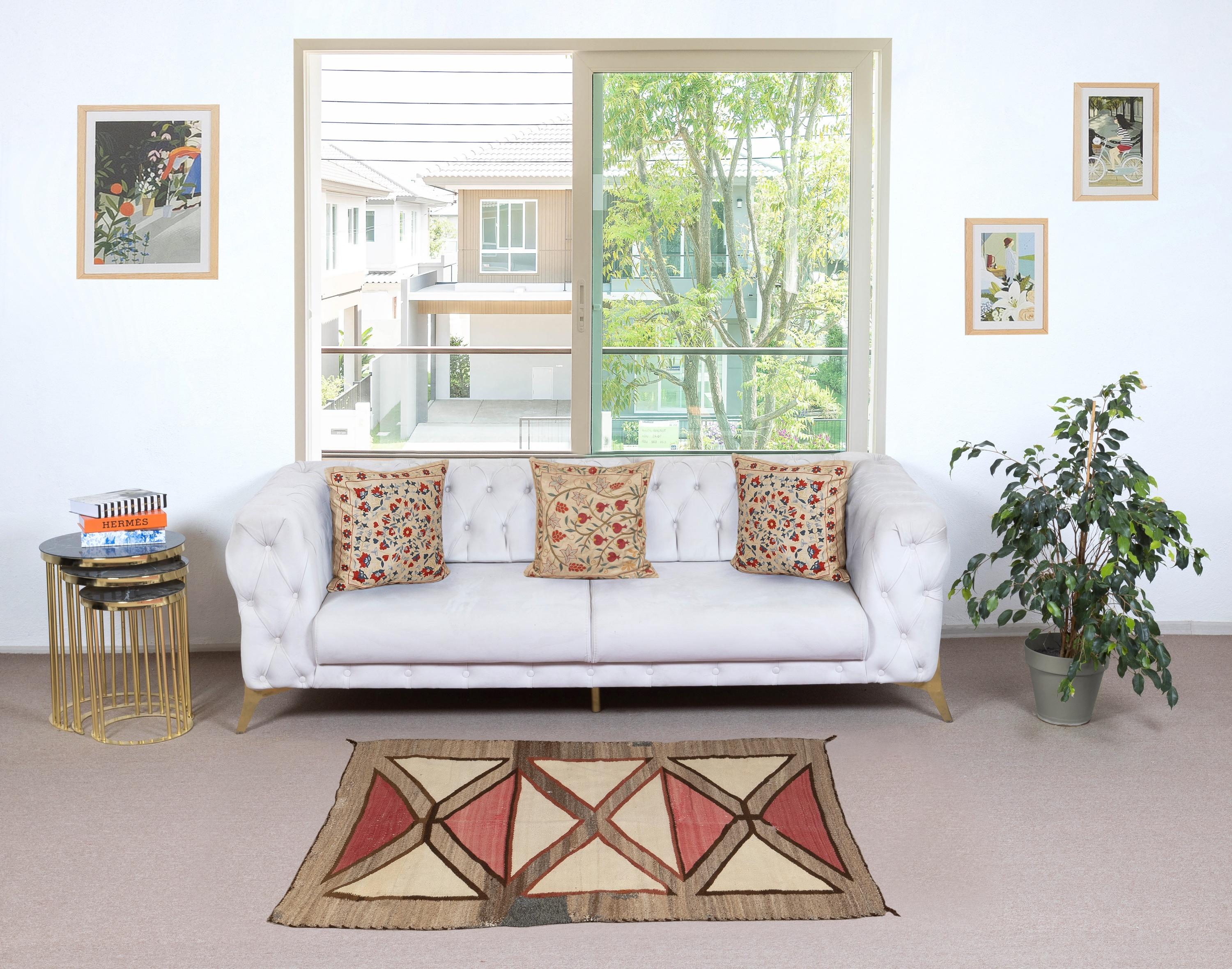 Un tappeto Navajo finemente tessuto a mano con un audace disegno geometrico a clessidra, creato all'inizio del XX secolo con lana filata a mano nei toni naturali non tinti del marrone e del grigio, accentuati dal rosso anilina