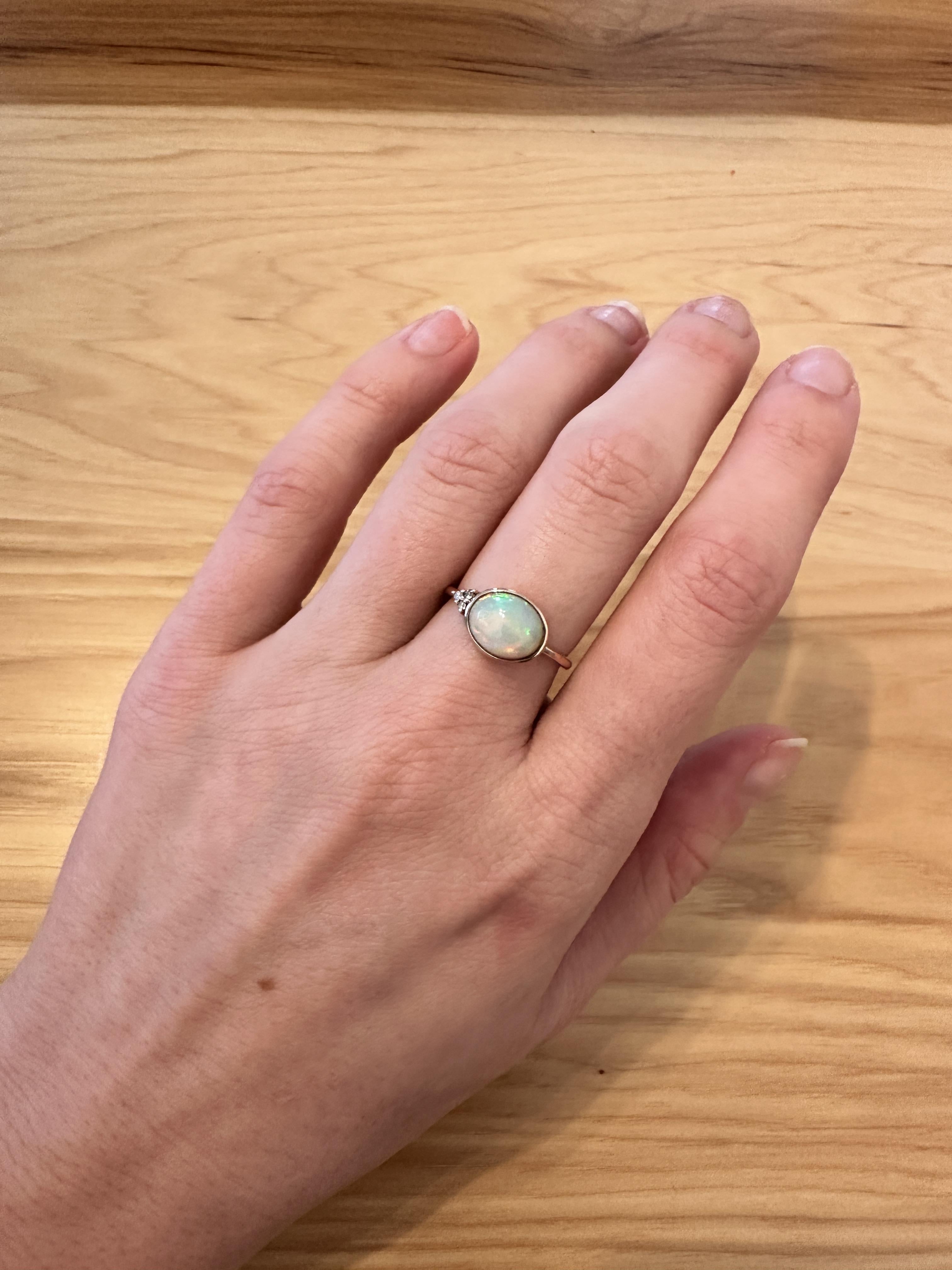 This lovely 1.98 carat opal has all the colors of the rainbow, accented with natural earth mined diamonds set in 14k yellow gold. An elegant bypass ring design makes this glowing ring perfect for the modern bride or that special someone in your
