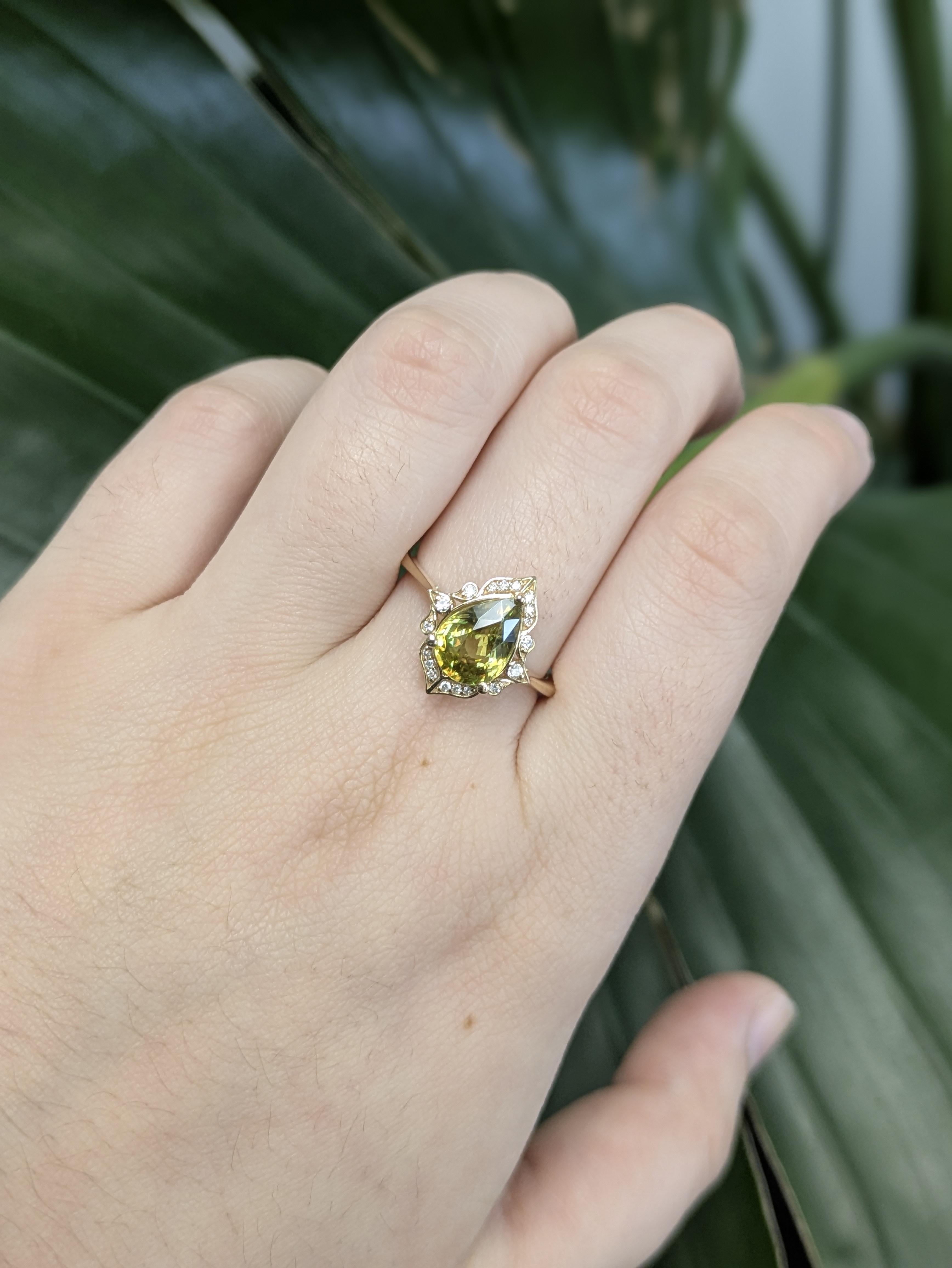 Este exquisito anillo presenta una esfena en forma de pera de 2,05 ct, conocida por su brillante fuego y vibrante color. Engastada en oro de 14k (2,83 g), la piedra central de 9x7 mm está bellamente acentuada por 18 brillantes diamantes que suman un