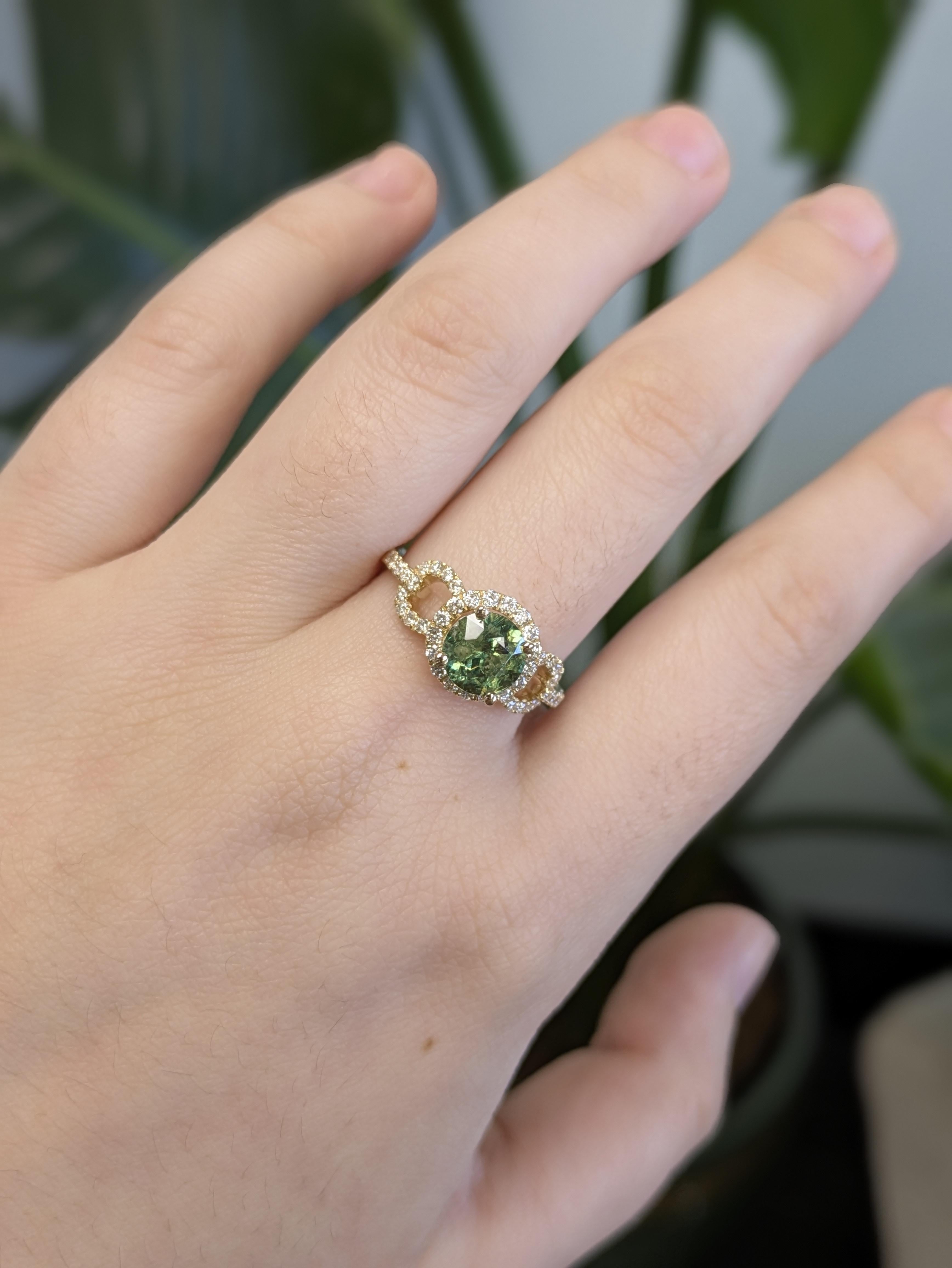Questo splendido anello in oro giallo 14K presenta un vibrante granato demantoide di taglio rotondo al centro, circondato da scintillanti accenti di diamanti naturali. Le ricche sfumature verdi del demantoide contrastano splendidamente con la calda