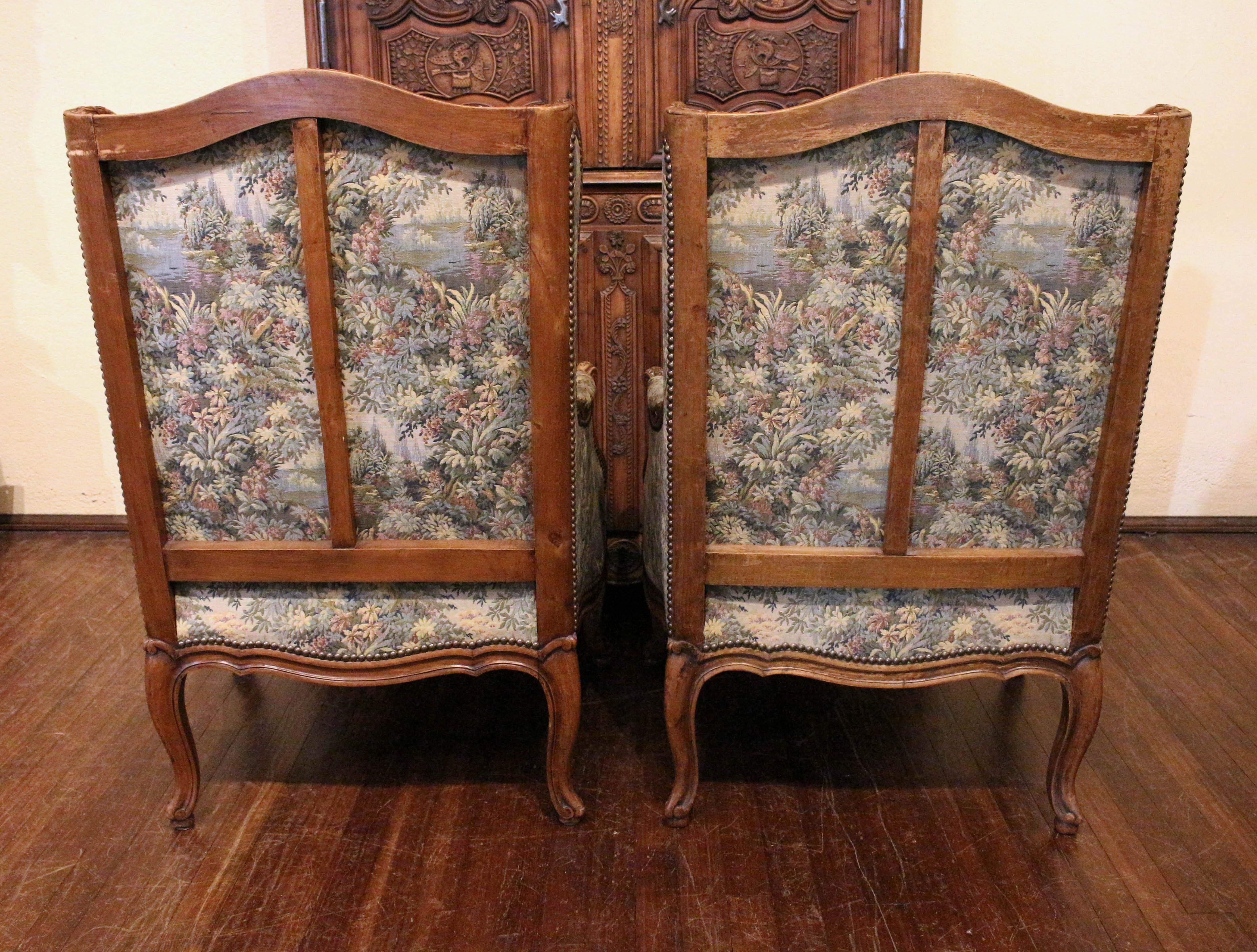 2nd quarter 20th century pair of Louis XV style Bergeres, French. Graceful & comfortable. Well carved walnut, fully developed on all sides. Shell, acanthus, rosette & bell flower carving. Cabriole legs ending in modified whorl feet. In French floral