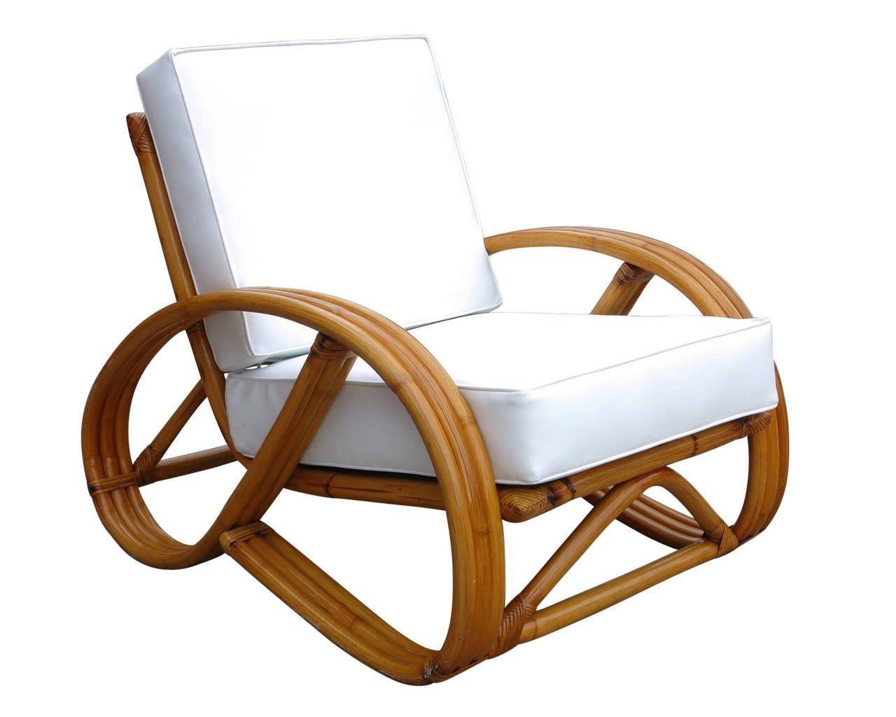 This round 3/4 pretzel arm rattan lounge chair has a unique decorative wave detail around the perimeter of the base. The accompanying bent rattan ottoman also features three strand U-shaped legs with matching wave detail. Professionally restored in