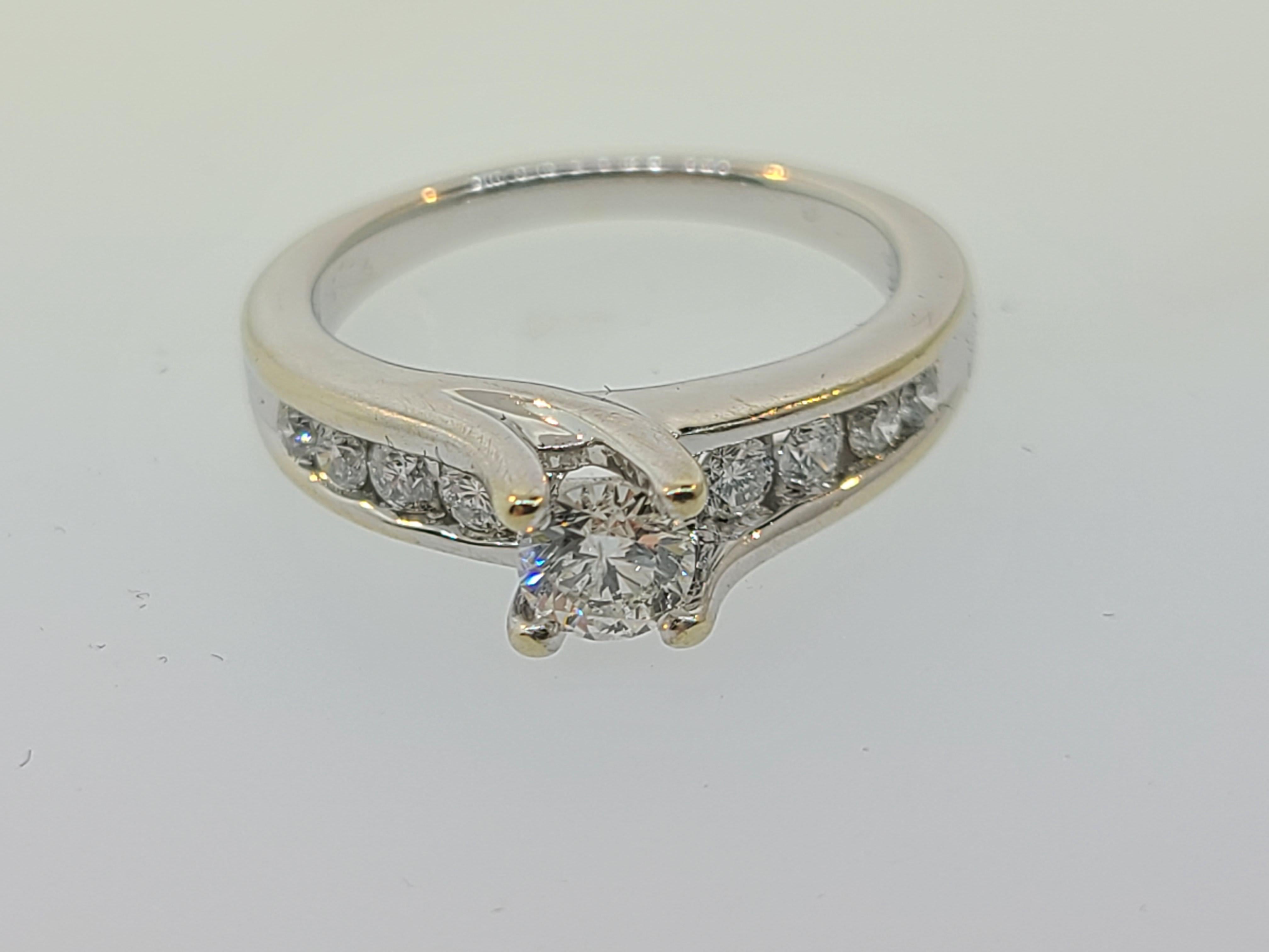 A beautiful contemporary engagement ring set in 14K white gold features a .45ct solitaire with graduated channel set diamonds on the shoulders which together are .75ctw. 

There is some finish loss to the rhodium plating which can be re-plated as