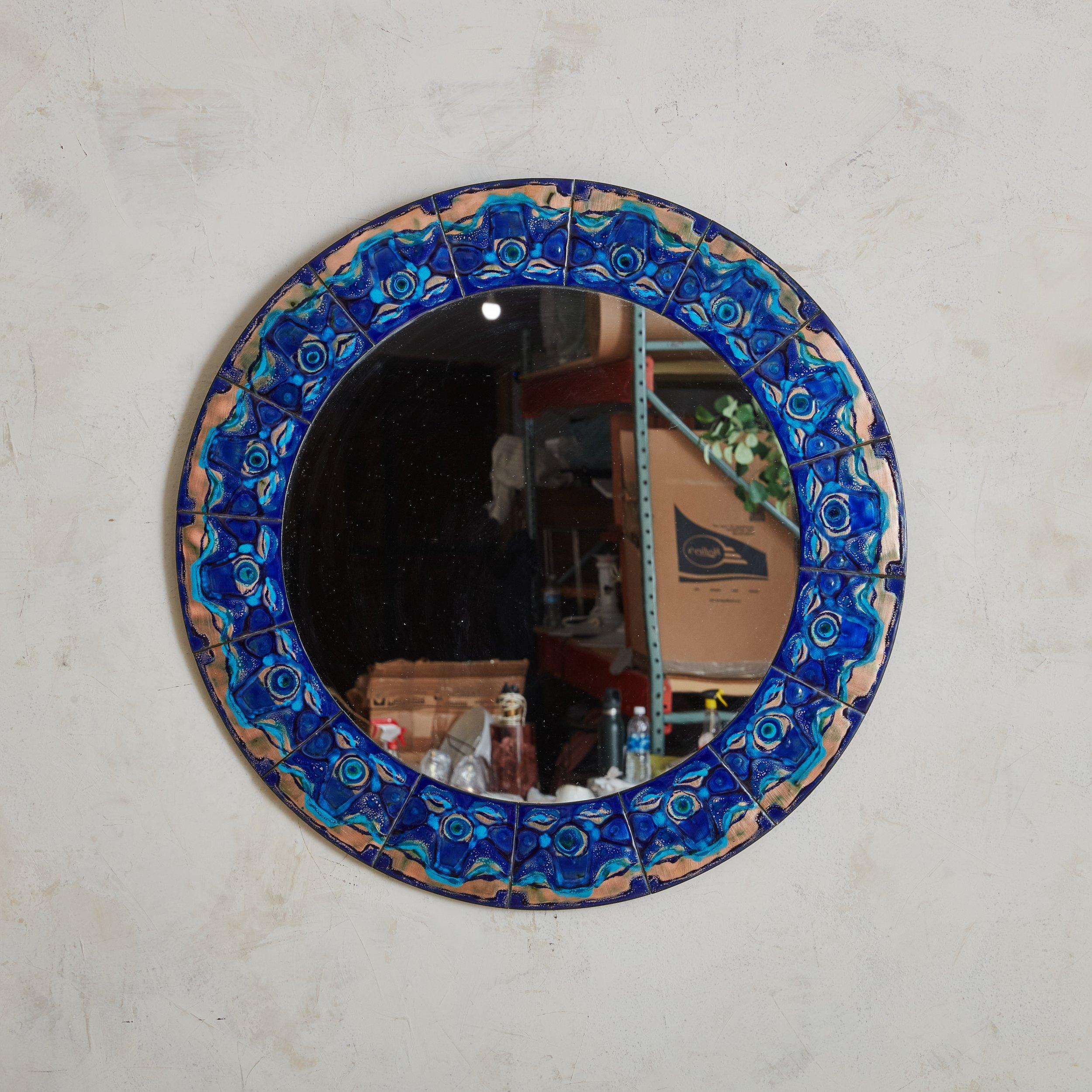 A Scandinavian Modern round wall mirror by Bodil Hagedorn Eje. Daughter of painter Thorvald Hagedorn-Olse, Bodil Eje was a Danish artist from the 20th Century who mostly worked with enamel. The mirror’s frame is composed of enameled copper plates