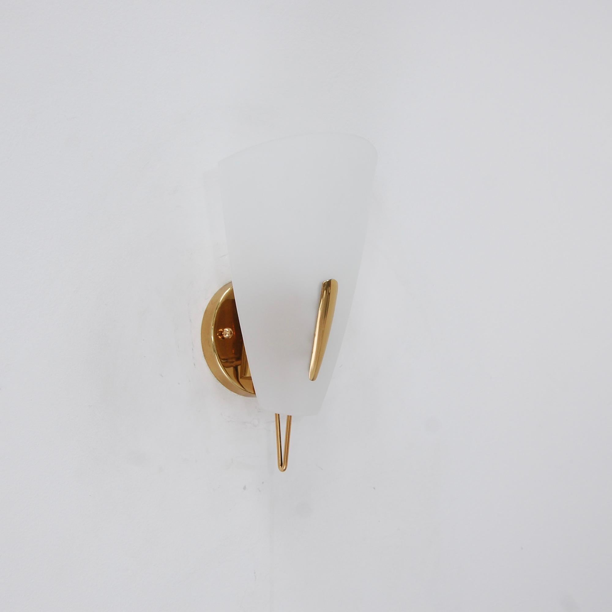 A lovely 1950s brass and glass shield sconce from Mid-Century Modern, Italy. Partially restored. Patinated brass finish and blown glass shade. Single E12 candelabra based socket. Currently wired for use in the US. 4” back plate. Priced individually.