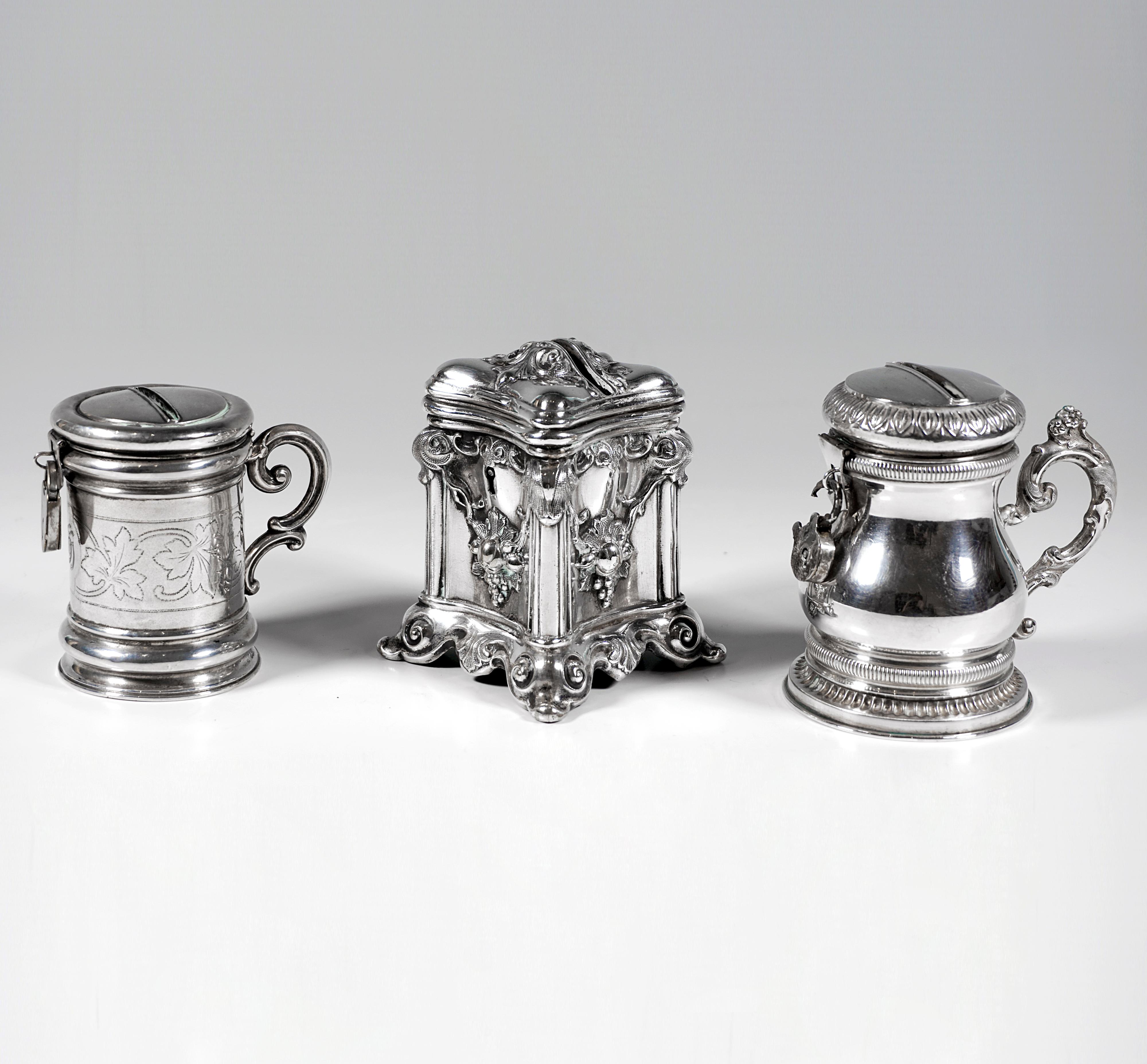Three silver money boxes, two in tankard form with padlocks, one in cuboid form with built-in lock, hinged lids.

Dating:           19th Century
Material:        Silver 13 Lot ('812.5')
Total weight:  ca 260 grams / 9.15 oz / 8.36 troy oz
Measures: 