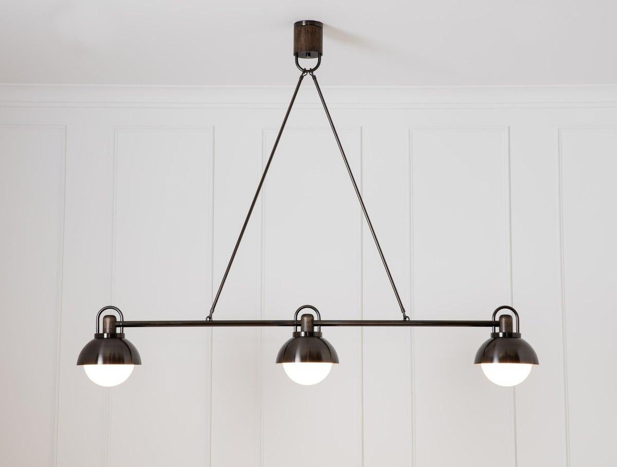 A contemporary take on a traditional billiard style fixture with meticulously fabricated joinery, bringing together three 10” pendants into one linear centerpiece.