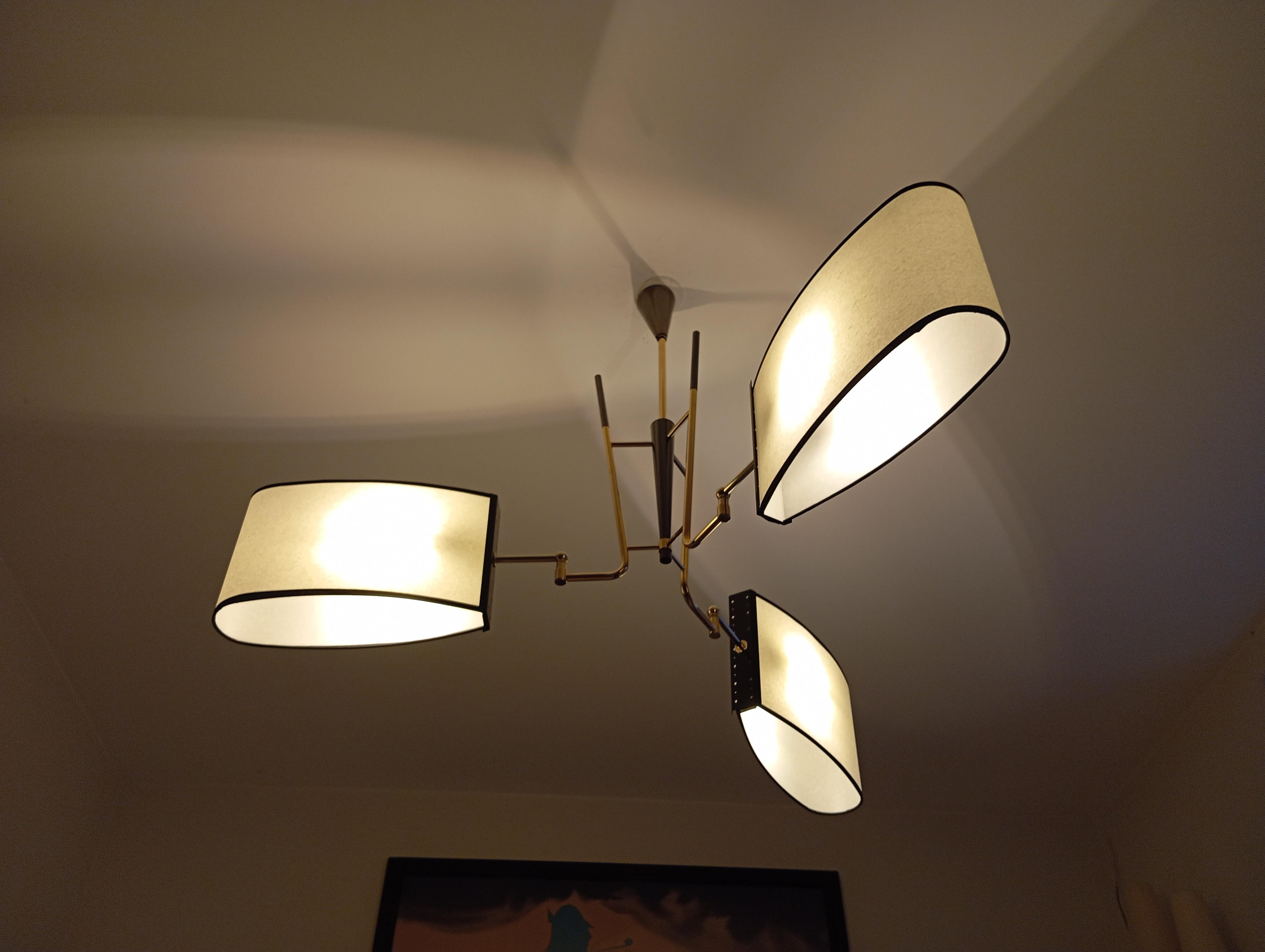 Lampadario con 3 bracci luminosi in ottone e ottone patinato canna di fucile.
 Composto da una base centrale conica, su cui sono disposti 3 bracci luminosi in ottone rifiniti con paralumi ovali.
 Opera francese del 1950 circa di Maison Lunel per