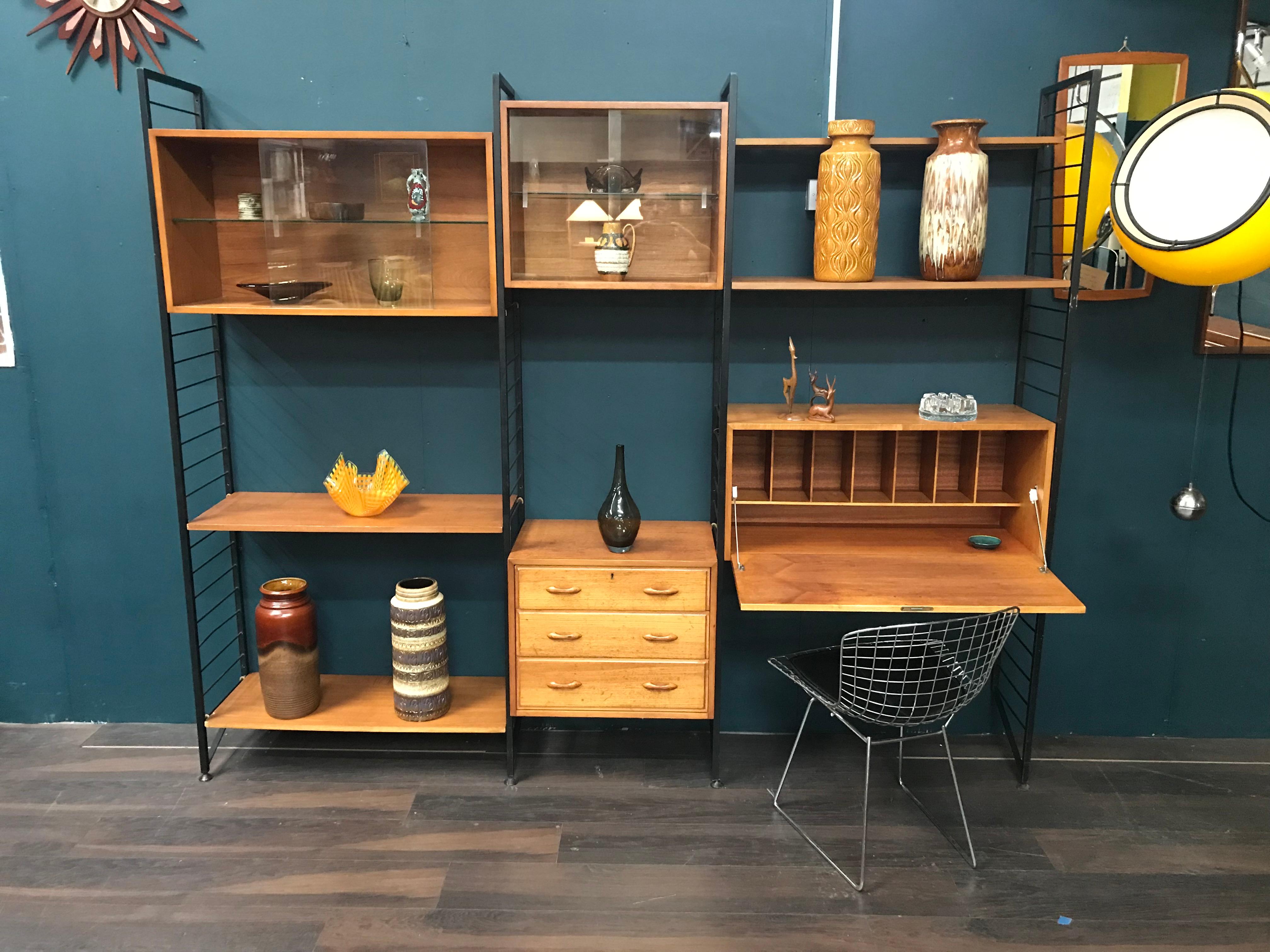 Stylish and functional, this is the classic Staples Ladderax midcentury shelving system. The black metal uprights and easy removable supports, allow the teak cabinetry to be positioned wherever required. This is a very versatile piece of retro