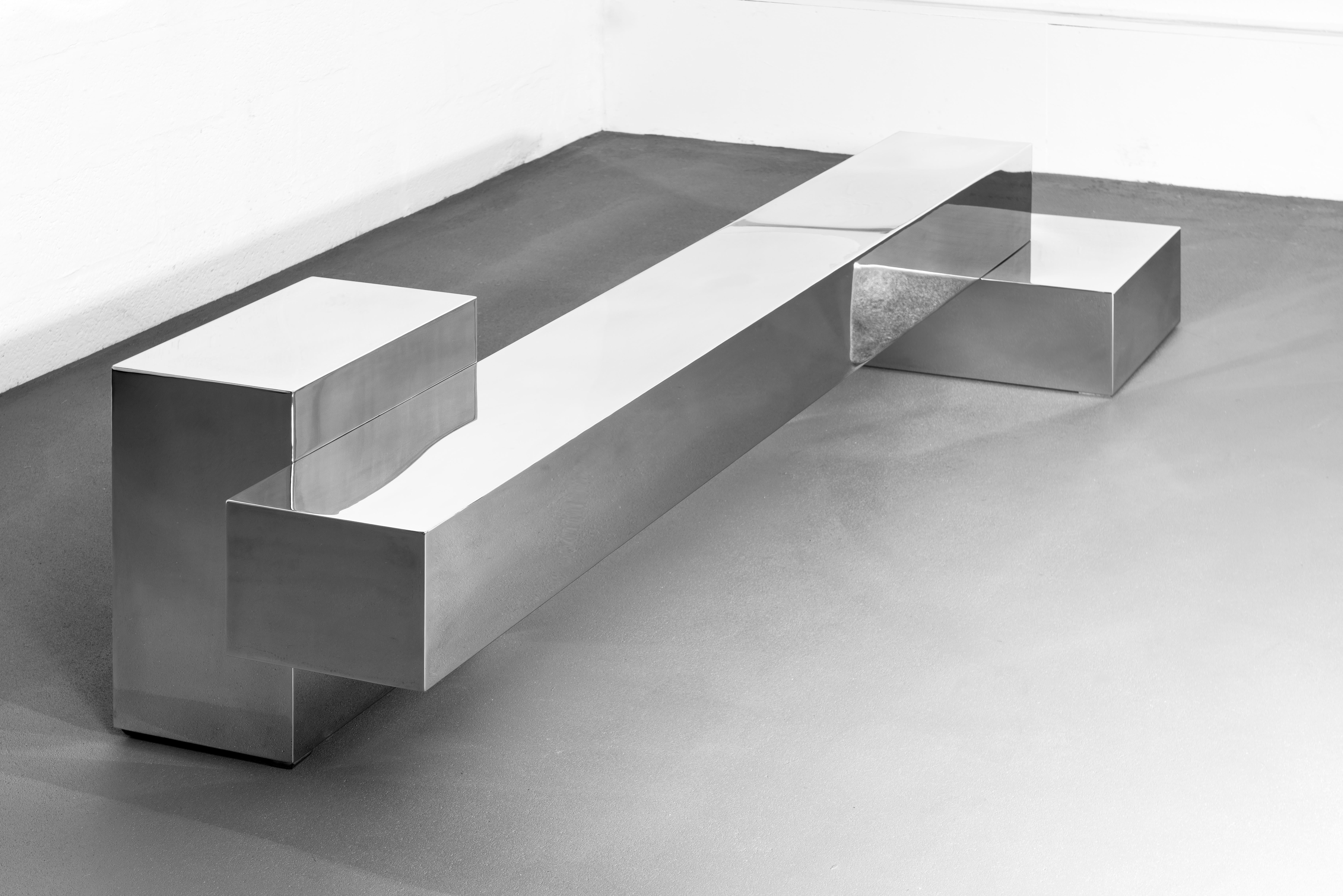 Table à 3 blocs de Pol Quadens 
Édition limitée à 8+4 pièces.
Dimensions : D 80 x L 200 x H 45 cm.
Matériaux : Acier inoxydable poli.

Pol Quadens est né à Bruxelles. Son père était actif dans les domaines des composites et de l'industrie
