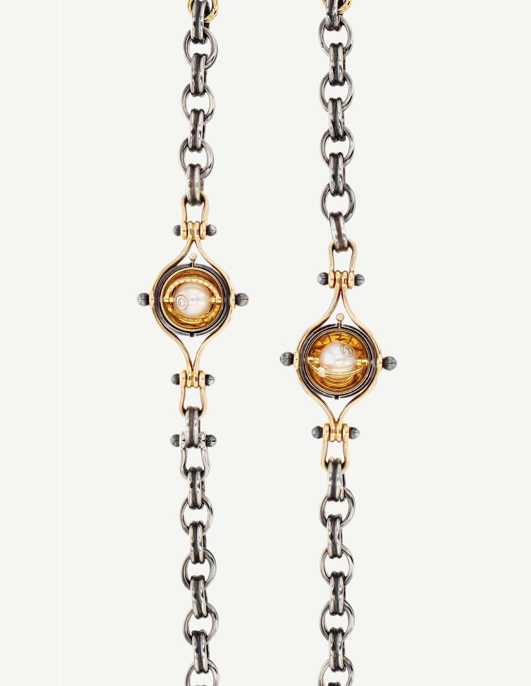 Pendant chain necklace made from distressed silver. Rotating spheres opening on an akoya pearl circled with a yellow gold satellite and diamond.