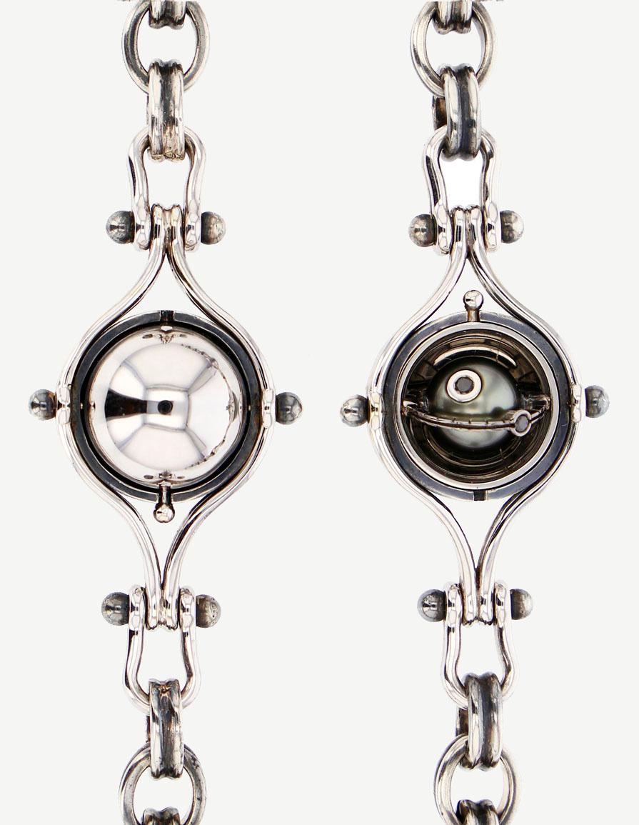 Pendant chain necklace made from distressed silver. Rotating spheres opening on a tahiti pearl circled with a white gold satellite and diamond.