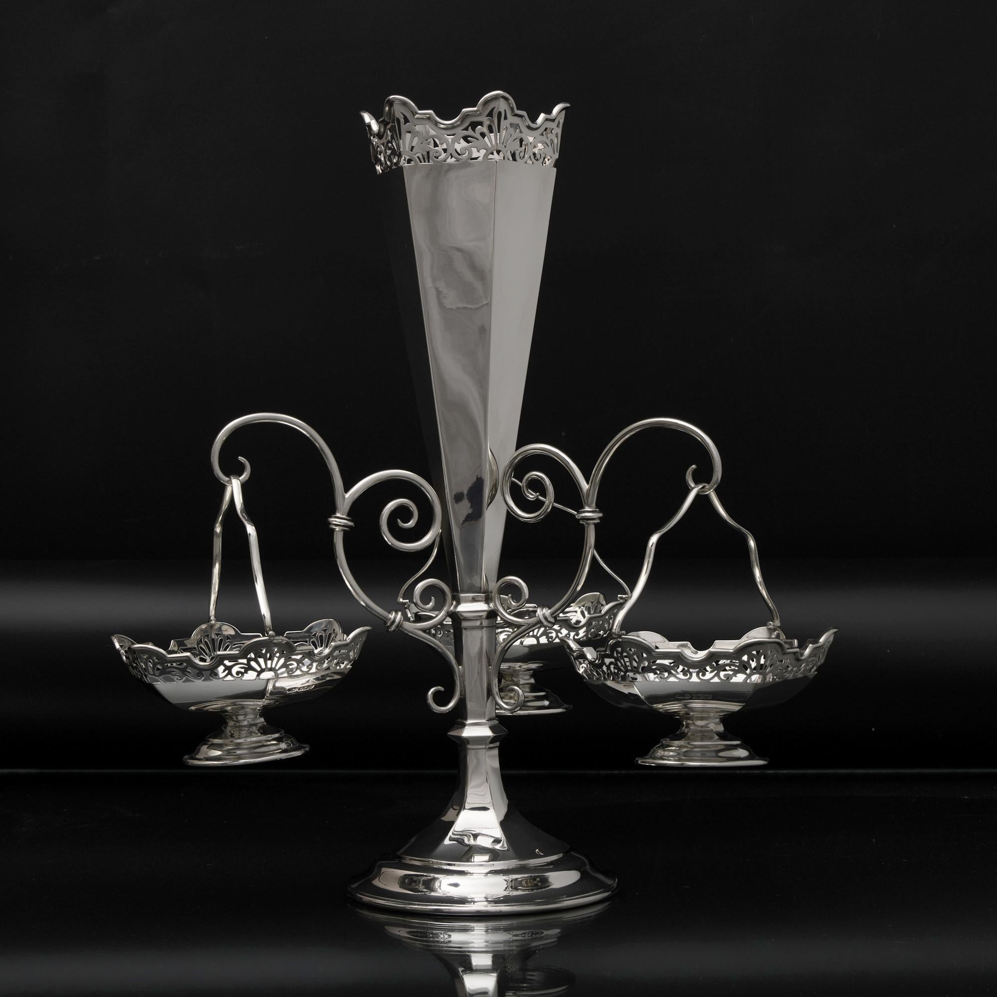 Centre de table en argent ancien de belle qualité, équipé de trois paniers amovibles suspendus à trois bras à volutes. Les corps hexagonaux du vase et des plats présentent des décorations percées de rinceaux en éventail et d'élégants rebords