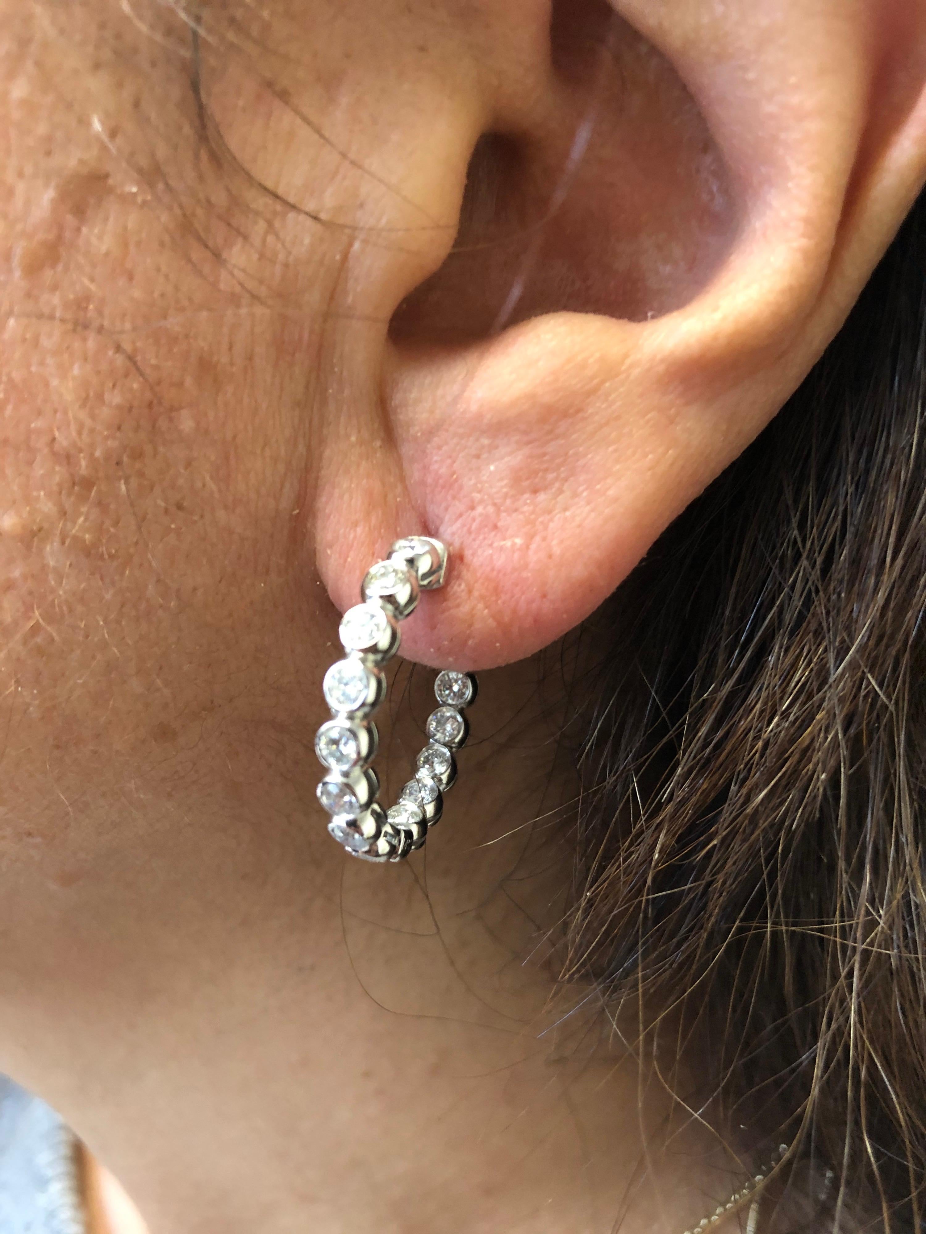 14K white gold diamond hoop earrings set in a bezel set. Each stone weighs 0.10 carats. The hoops are set inside and out. The diameter of the hoops are 3/4 of an inch. The total carat weight is 2.87 carats. The color of the stones are G, the clarity