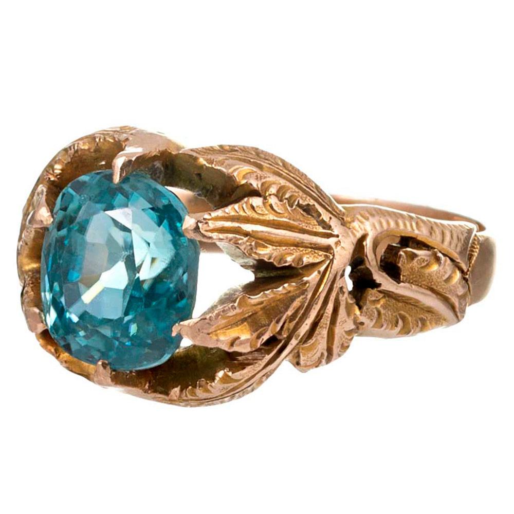 Lifelike and finely detailed leaves of 14 karat yellow gold contain a 3 carat blue zircon nestled within their foliage. The absence of diamonds makes this ring suitable for any occasion and the bright, unusual color hue will encourage compliments.