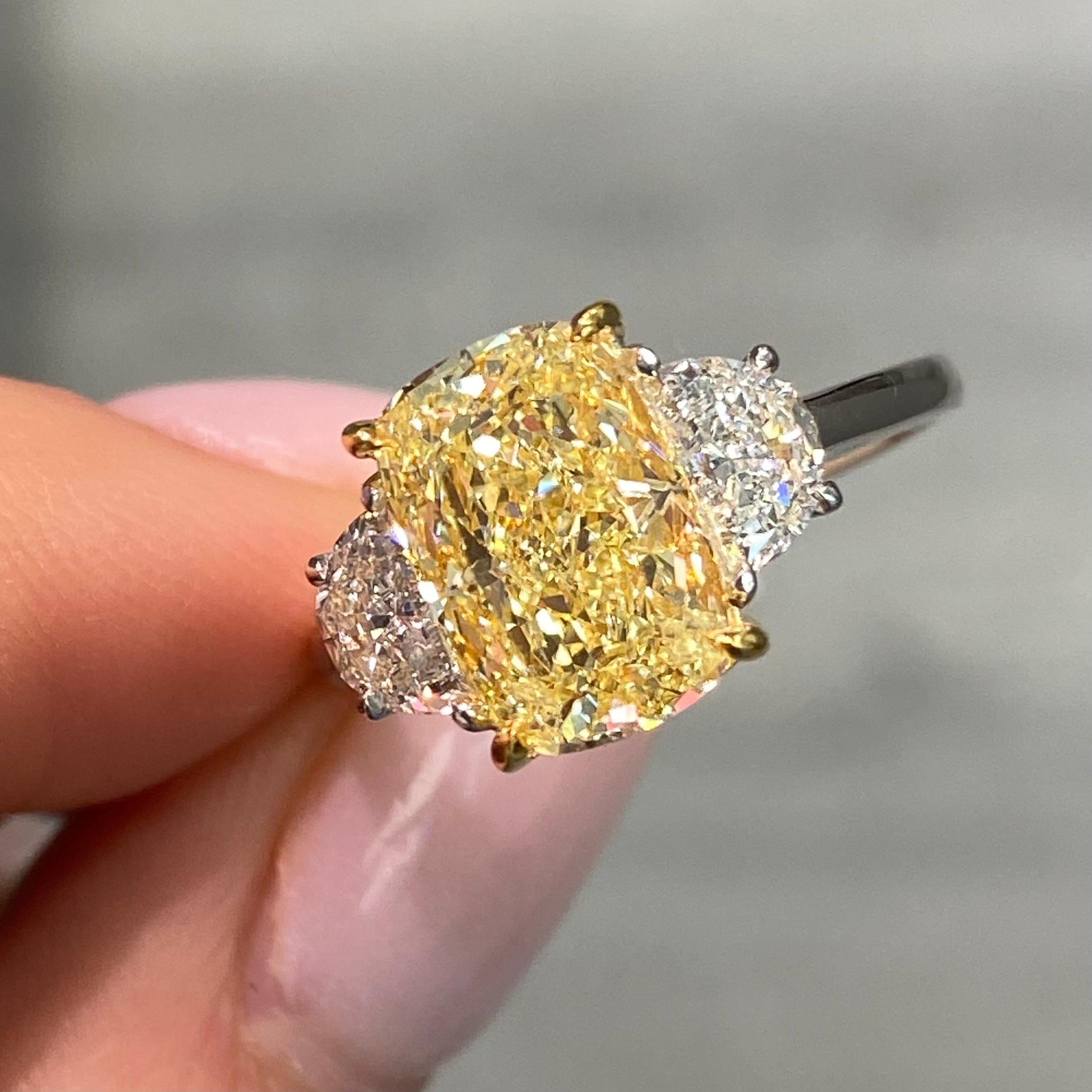 Dieser Dreisteinring besticht durch seine schlichte Eleganz mit einem 3,01-karätigen hellgelben Fancy-Diamanten in der Mitte. Der kissenförmig geschliffene Diamant hat eine weiche, schmeichelhafte Silhouette, die sein sanftes Glühen noch
