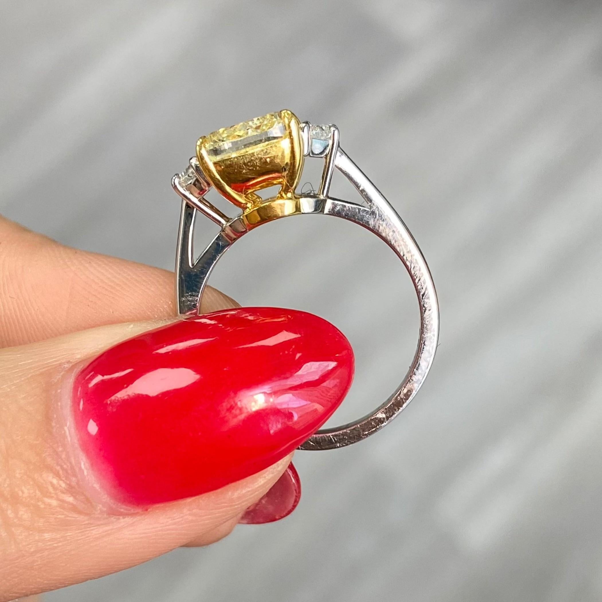 This 3-carat Fancy Yellow cushion-cut diamond engagement ring is a stunning embodiment of elegance and luxury. The vibrant yellow hue of the center diamond exudes warmth and sophistication, making it a truly remarkable piece.

The cushion cut