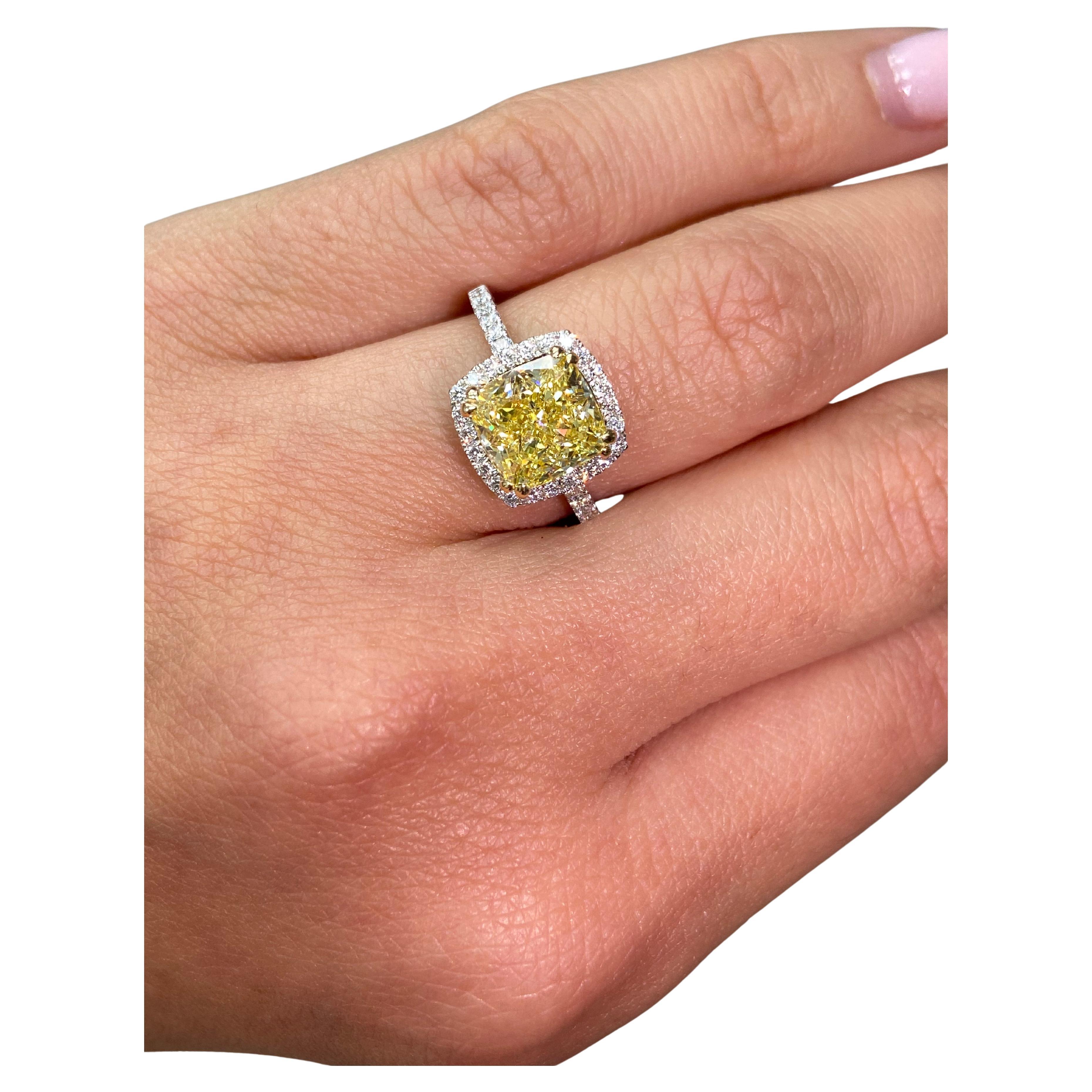 Celebrate your love with this exquisite 3.01 Carat Fancy Yellow Diamond Engagement Ring, a masterpiece of craftsmanship and elegance. The centerpiece, a breathtaking cushion-cut Fancy Yellow diamond, boasts a remarkable 3.01 carats and SI2 clarity,