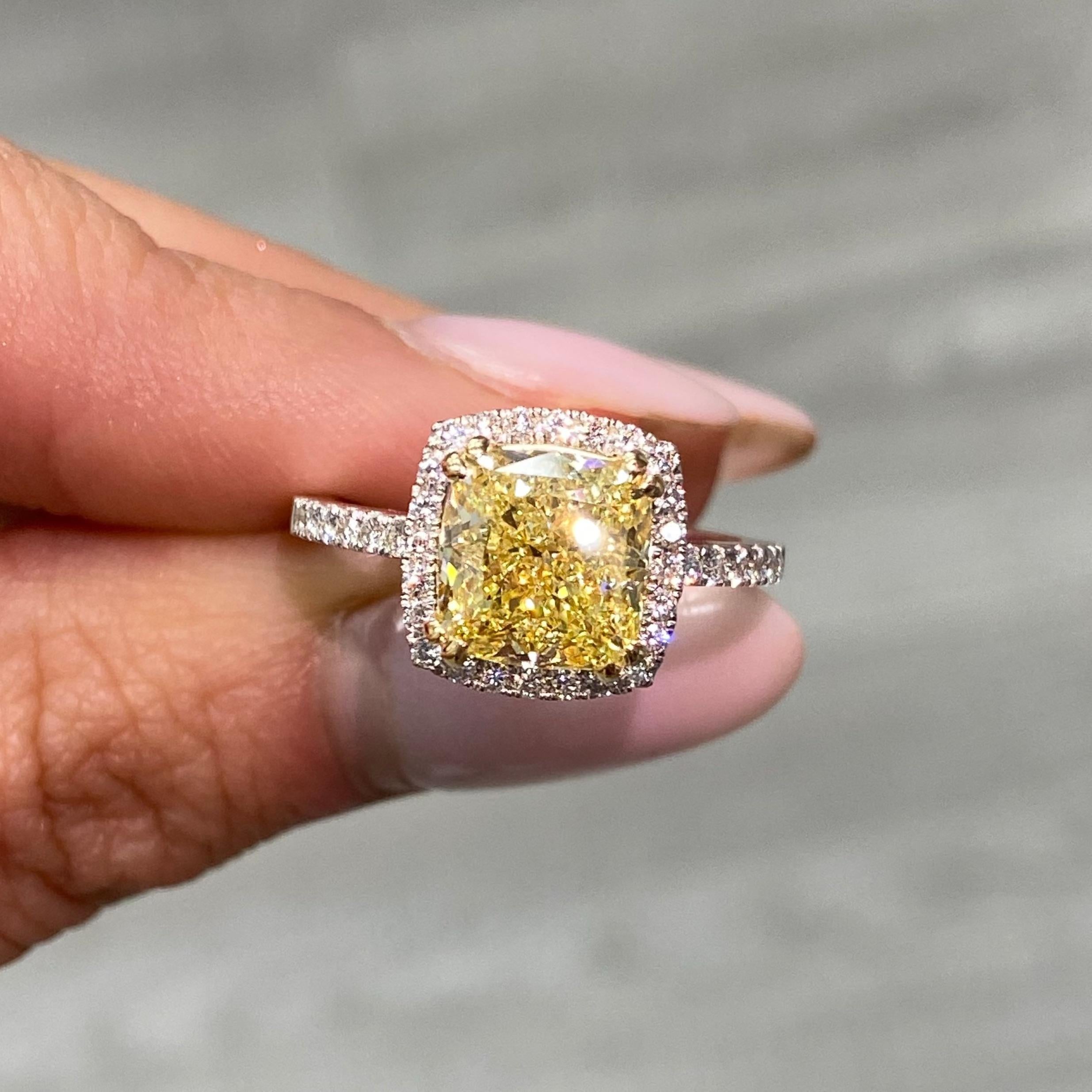 This stunning yellow diamond engagement ring is the epitome of timeless elegance, designed to captivate the heart and the eye. The 3.01-carat cushion-cut fancy yellow diamond is beautifully framed by a halo of 0.32 carats of dazzling white round