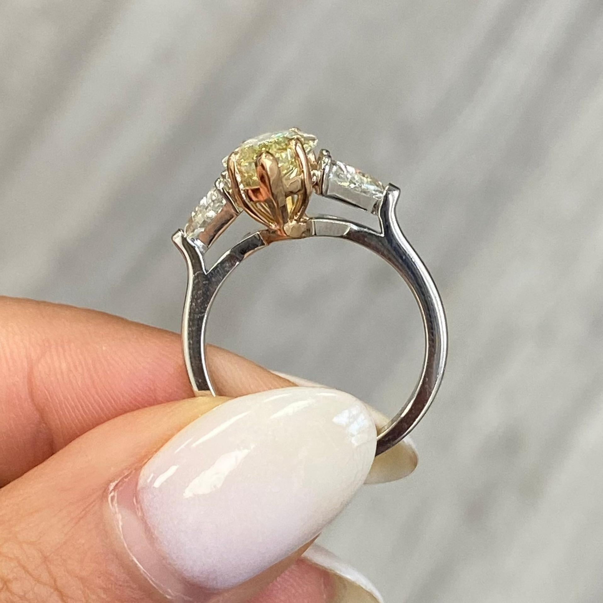 Elegant and unique 3.39 carat center fancy yellow marquise cut diamond with VS2 clarity set in a platinum and rose gold ring with trillion side diamonds weighing 1.01 carats. 
GIA Certified Yellow Diamond.  

At Rare Colors, you can experience the