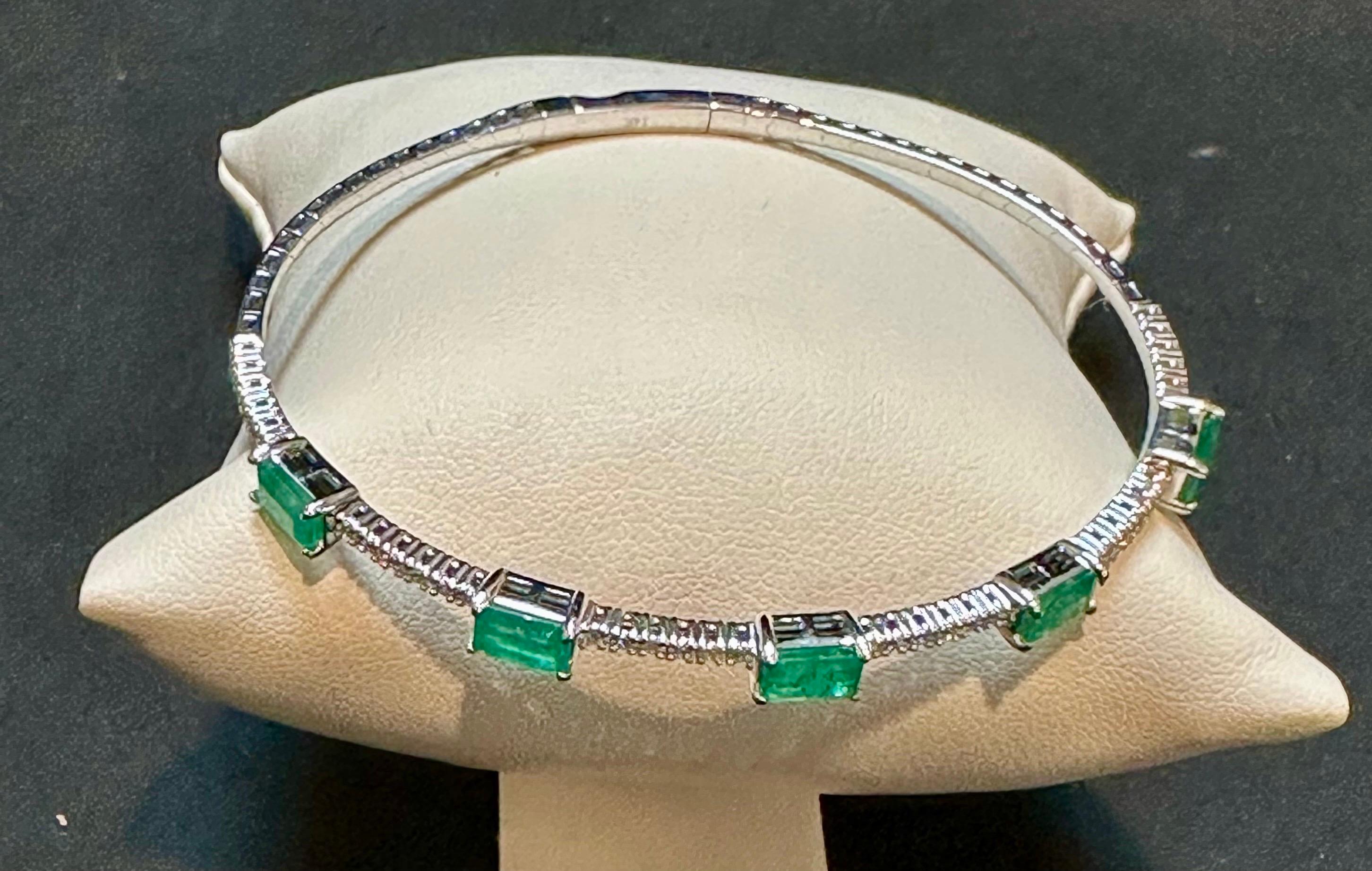 Introducing our exquisite 14 Karat Yellow Gold Bangle Bracelet adorned with approximately 3 carats of Natural Brazilian Emeralds and sparkling diamonds. This bangle bracelet showcases five emerald-cut emeralds, each meticulously separated by a row