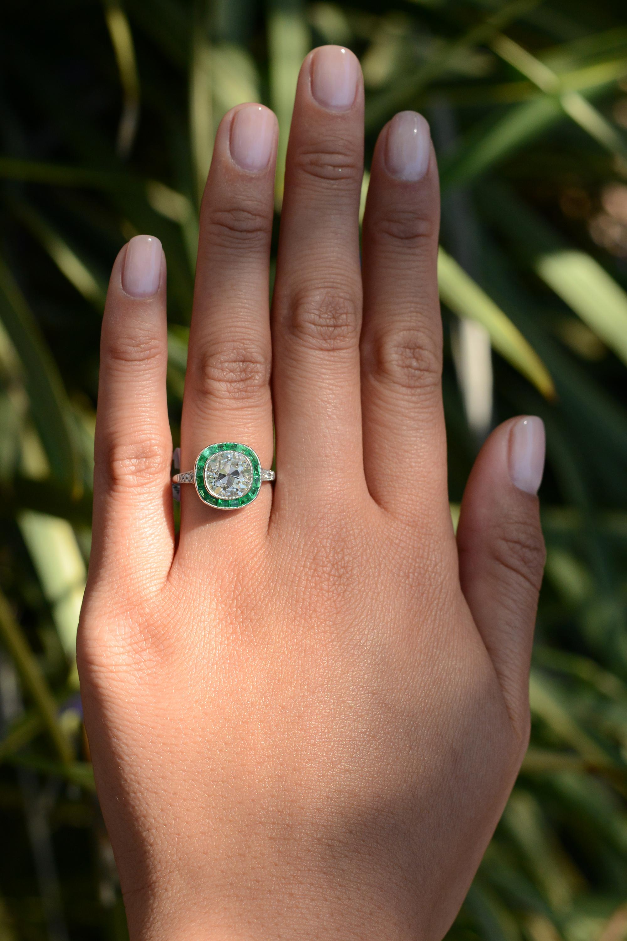 This dreamy engagement ring combines a charismatic, antique cushion diamond with a simple, yet unique emerald halo. The near 3 carat antique diamond has all the personality we love in an old mine cut diamond with remarkable sparkle and impeccable