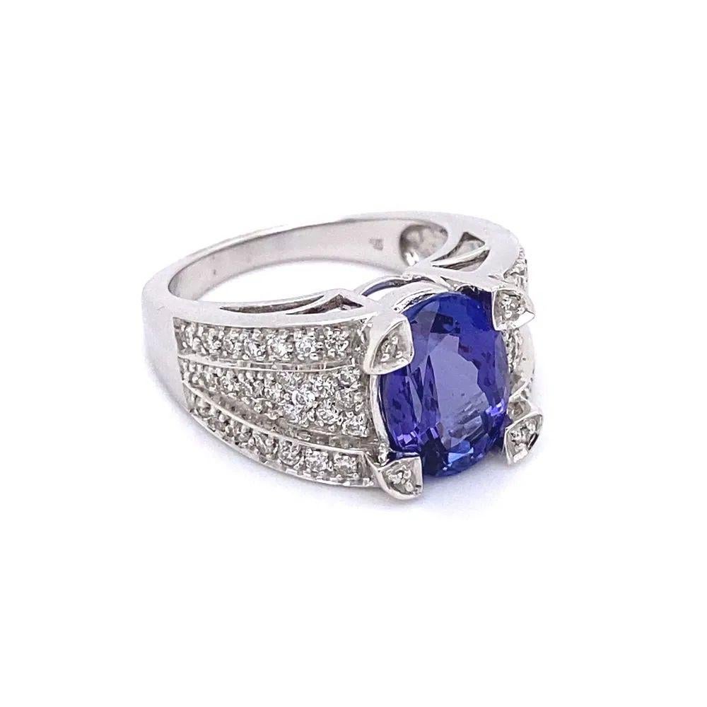 Simply Beautiful! Finely detailed Oval Tanzanite and Diamond Gold Ring. Centering a securely nestled Hand set 3 Carat Oval Tanzanite. Accented either side by Sparkling Diamonds, approx. 0.38tcw. Hand crafted 18K White Gold mounting. Size 6.75, we