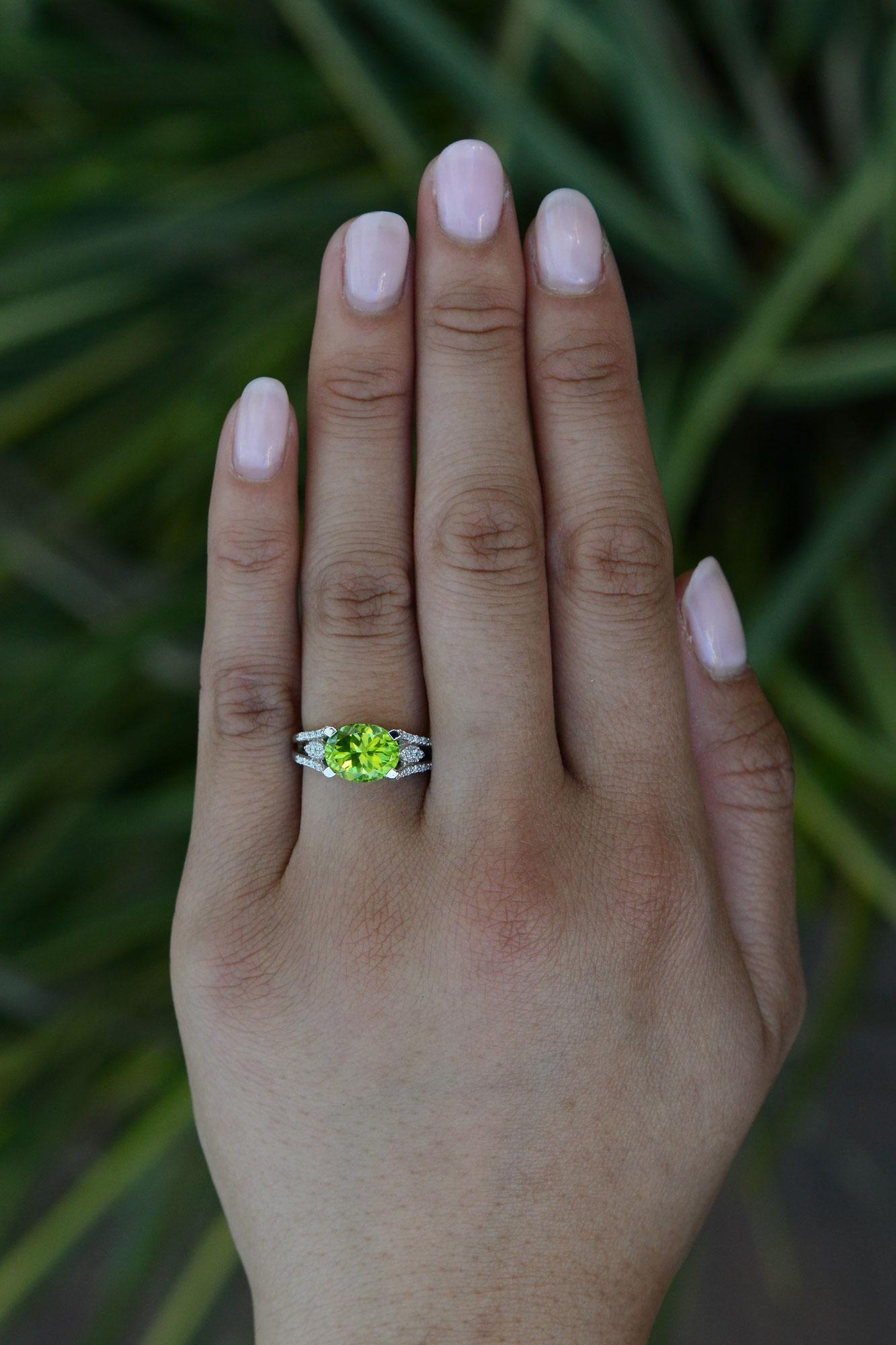 A lovely and calming 3 carat peridot engagement ring, with a robust contemporary design. This gemstone engagement ring is centered by a vivid, rich green oval, interestingly set in an East-West orientation. Known to increase strength and vitality,