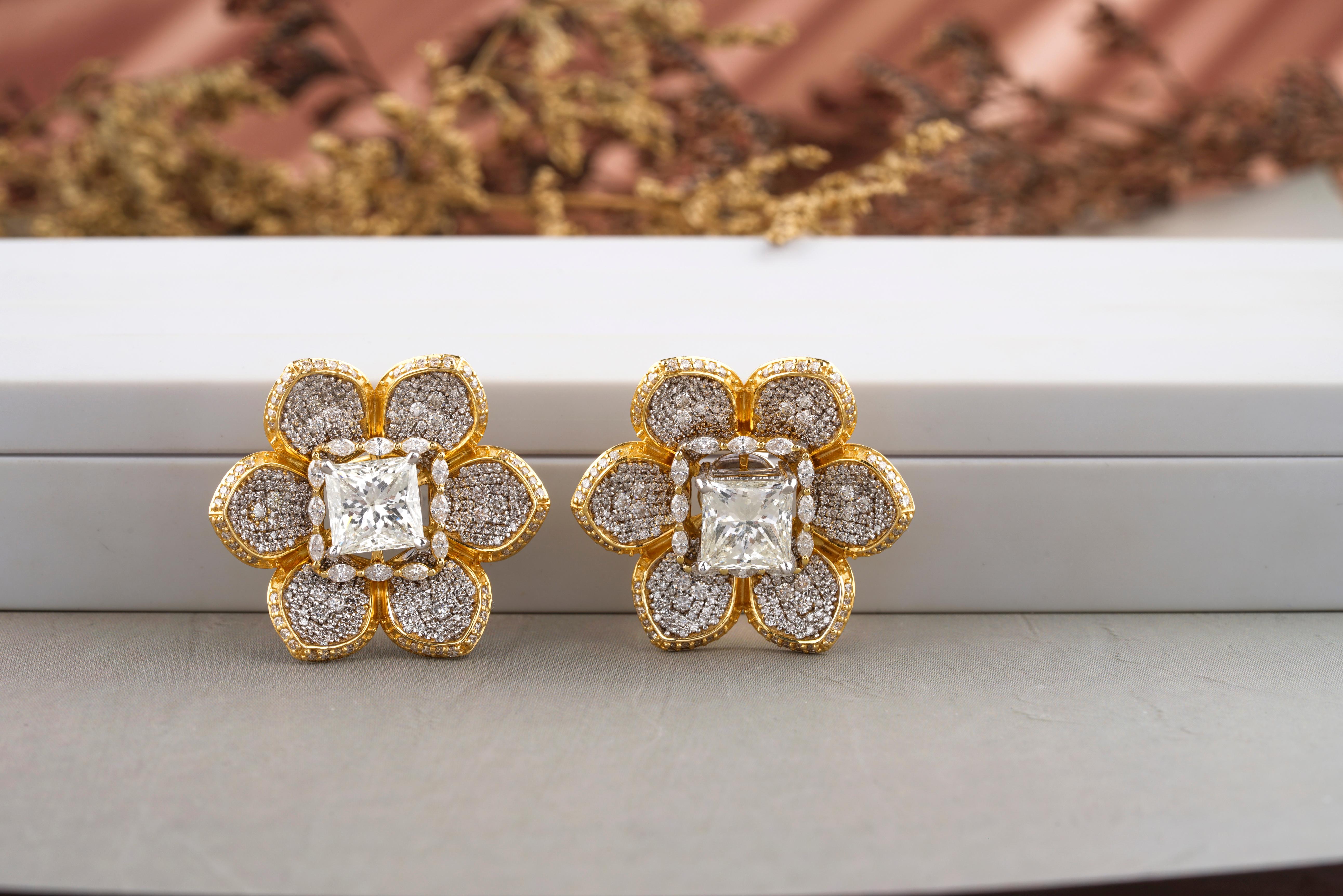 These earrings feature a princess-cut diamond in a simple and elegant solitaire setting made from 18K solid gold, surrounded by a delicate floral design jacket, which is designed to accentuate the simple solitaire, adding an extra element of