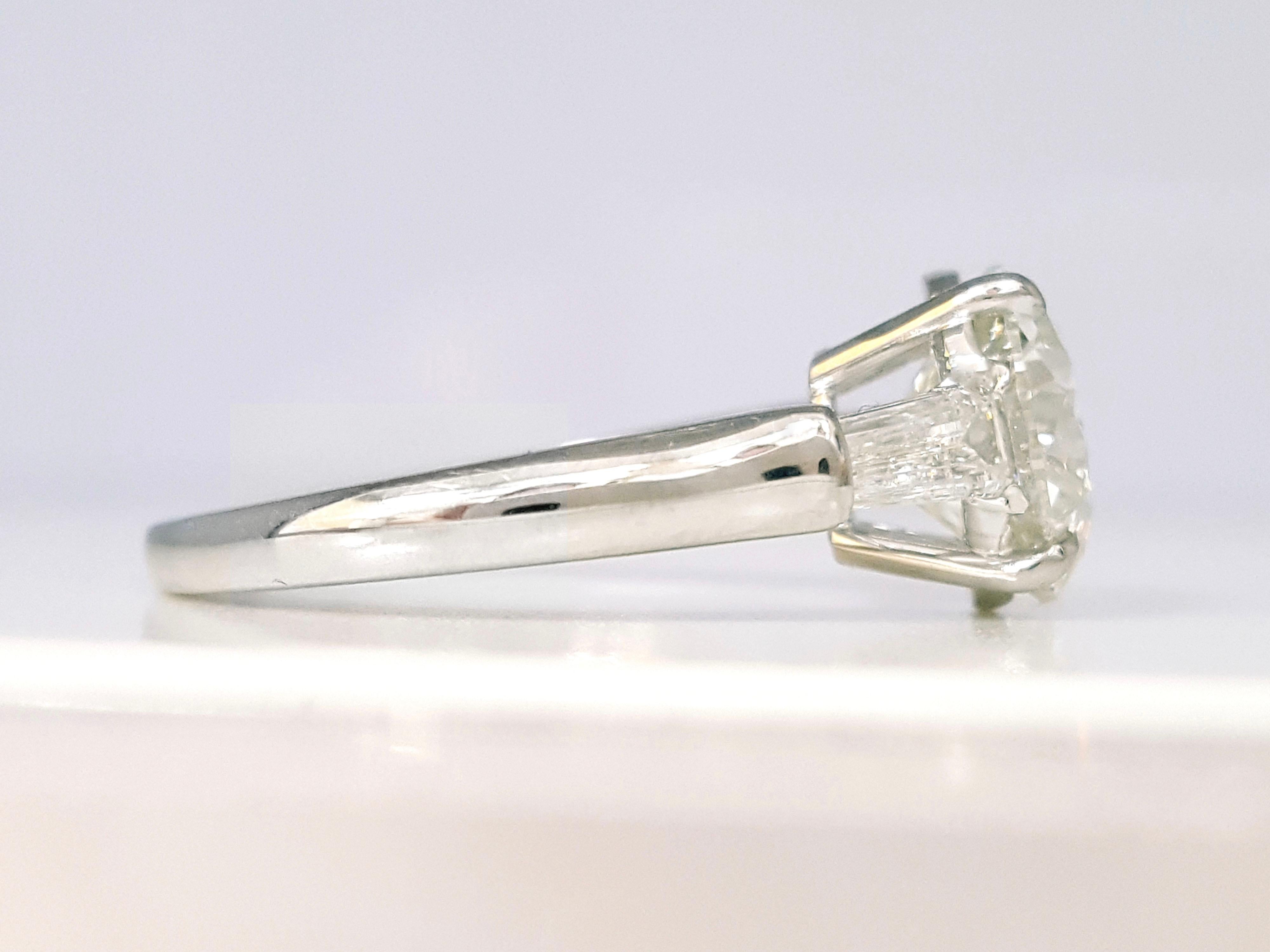 Bague de fiançailles spectaculaire réalisée en platine, présentant un diamant rond de taille brillant certifié par le GIA pesant 3.01 carats, couleur I, pureté SI2, accentué par deux diamants trapèzes pesant approximativement 0.58 carats au total,