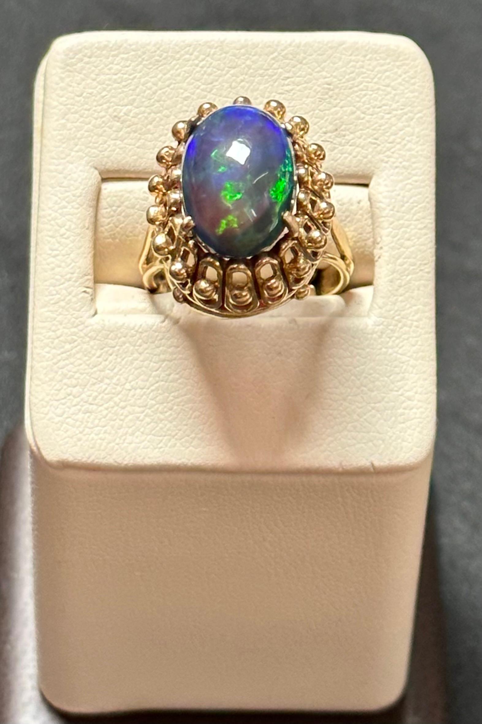Introducing our extraordinary 14 Karat Yellow Gold Cocktail Ring showcasing a dazzling 3.0 carat oval-shaped Black Australian Opal. This magnificent piece displays stunning shades of green and blue, creating a mesmerizing spectacle. 

The opal in