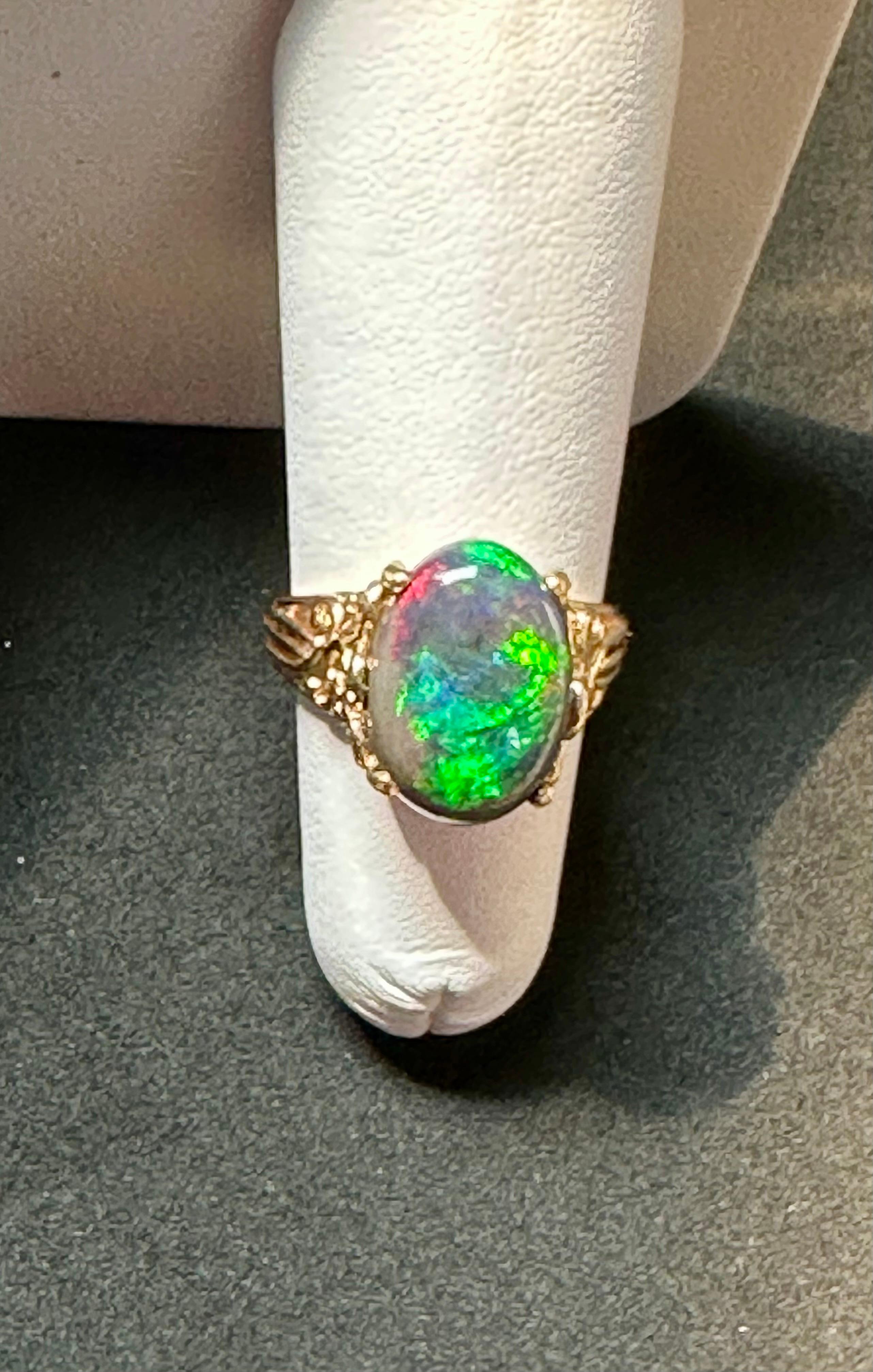 Introducing our captivating 14 Karat Yellow Gold Cocktail Ring featuring a breathtaking 3 carat oval-shaped Black Australian Opal. This remarkable piece showcases the opal's mesmerizing shades of green and blue, radiating with a brilliant luster and